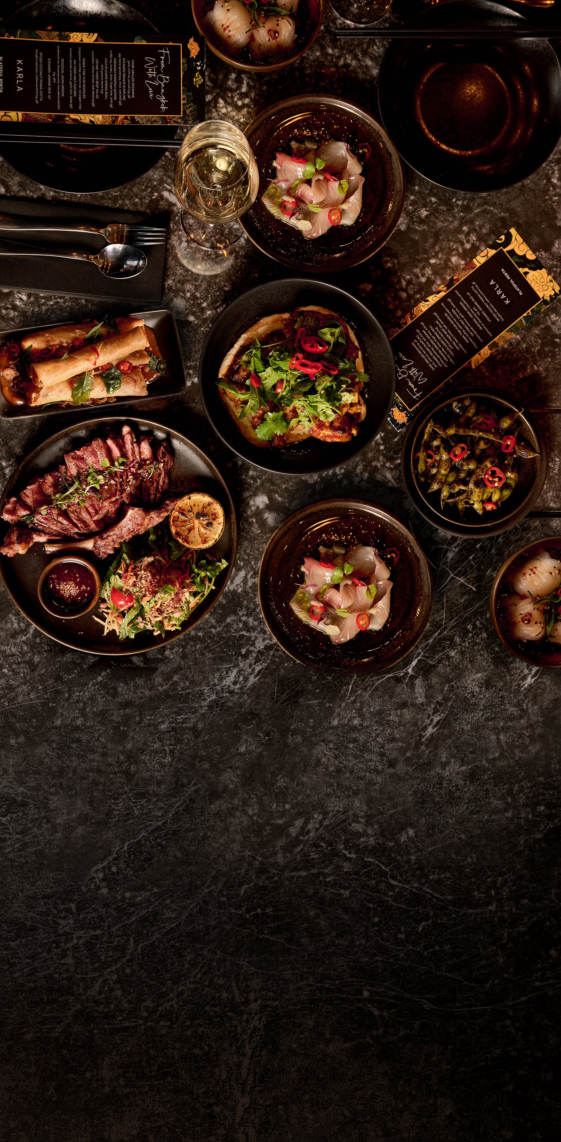 Table with plates of ceviche, steak with lemon half, vegetables