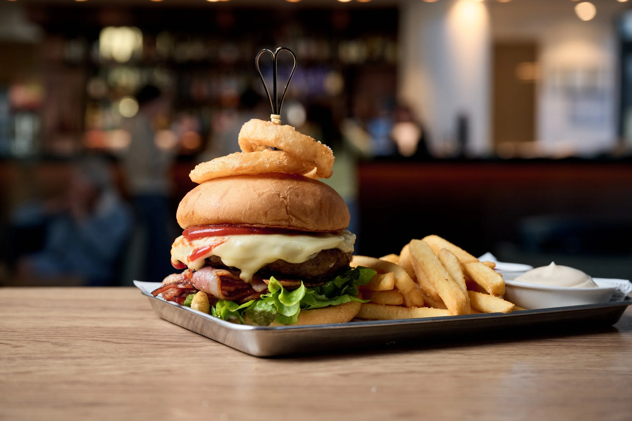 Burger with onion rings, melting cheese and chips with sauce