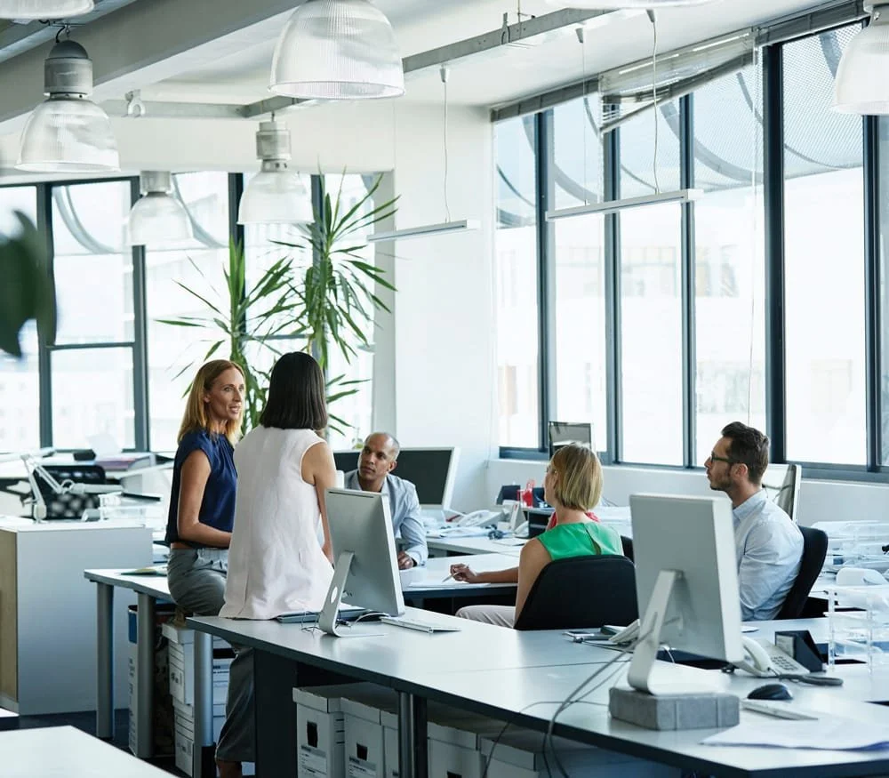 Workplace experience Fünf Kollegen in einem modernen Büro bei einer Besprechung.
