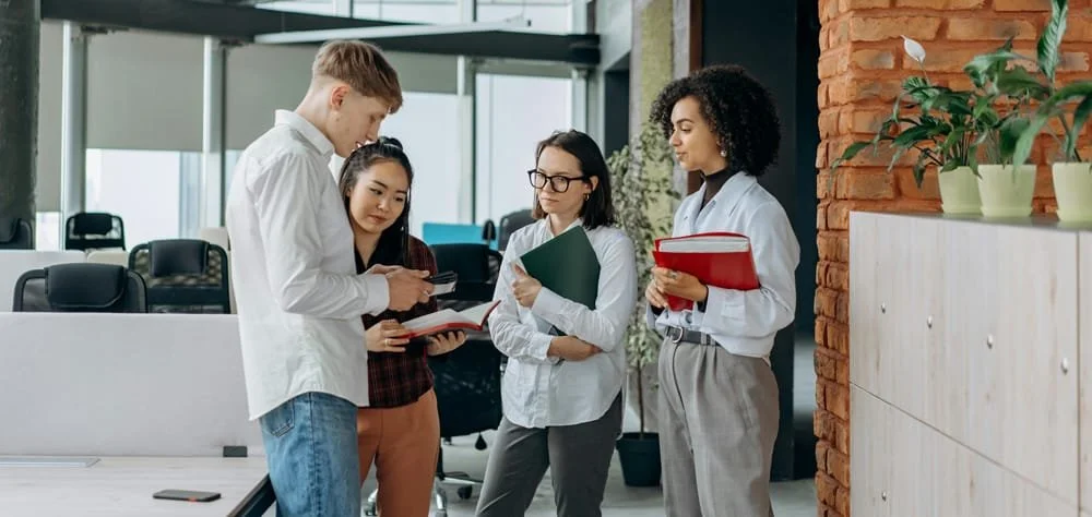 Kollegen arbeiten gemeinsam an einem Schreibtisch und nutzen digitale Tools im Büro
