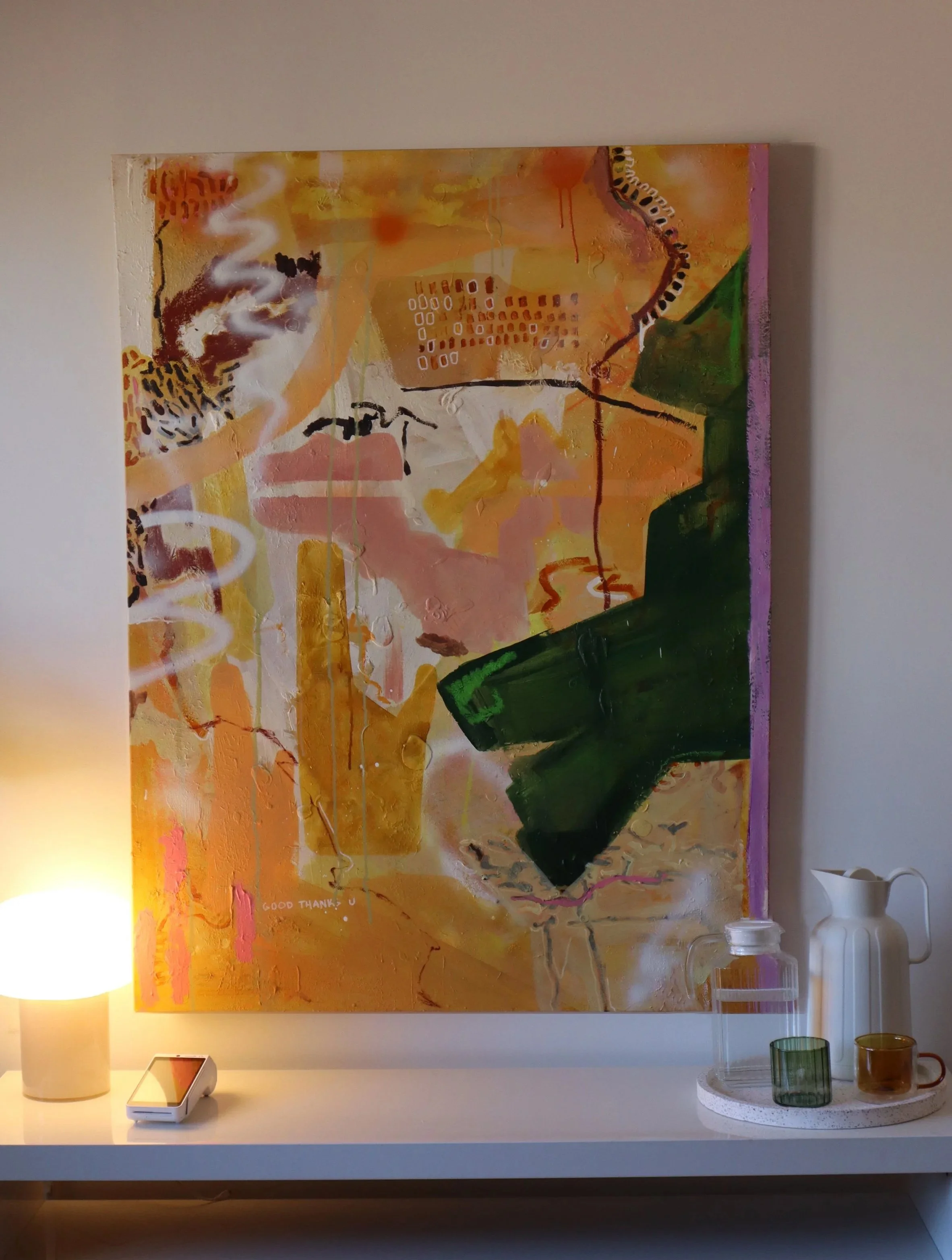 Abstract painting with warm colors, black and white markings, some geometric shapes, and a pink border. The phrase 'GOOD THANK YOU' is faintly visible on the lower left side.