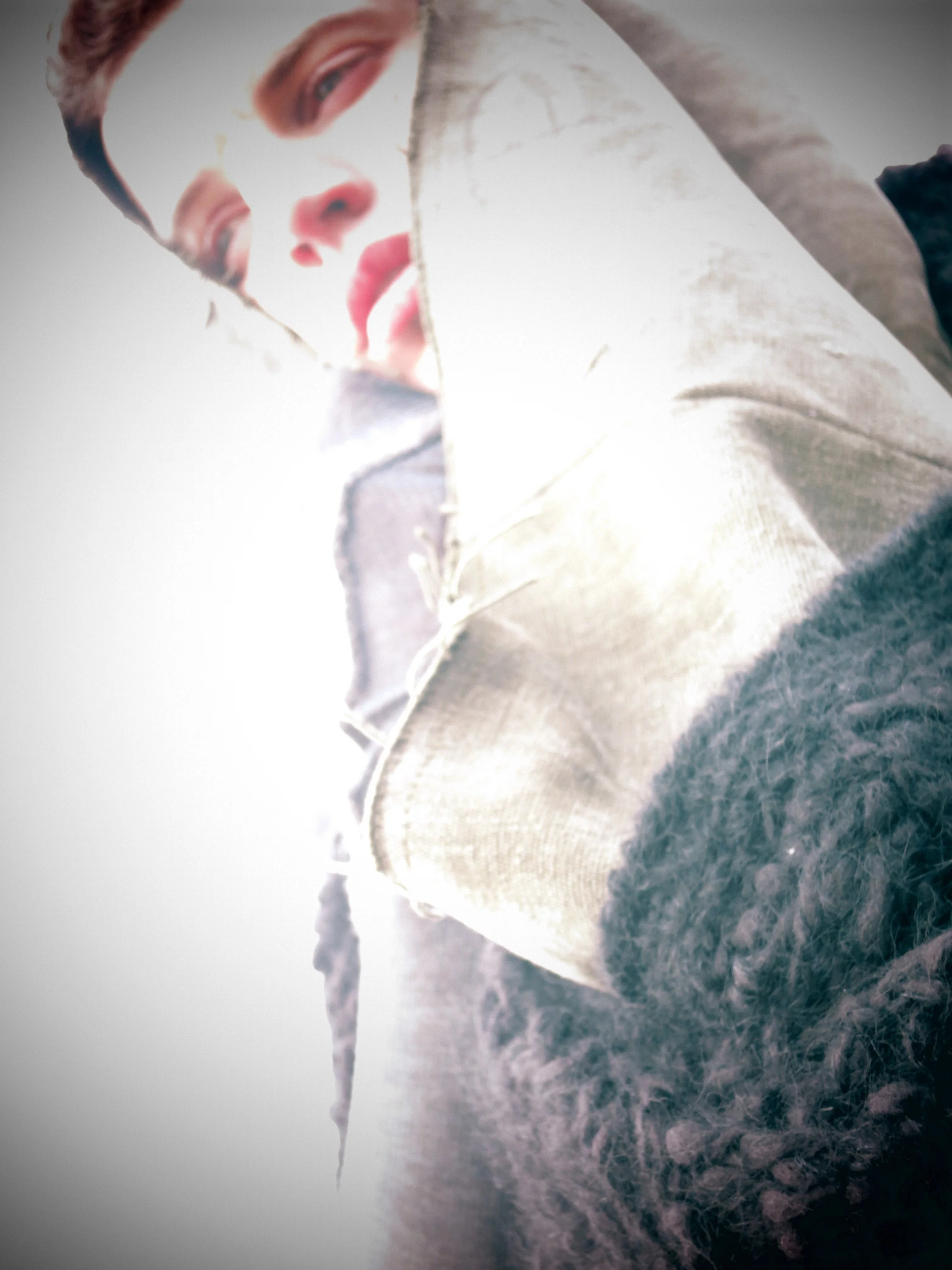 Close-up of a person lying on snow-covered ground, wearing a winter coat with furry trim, looking up at the sky.