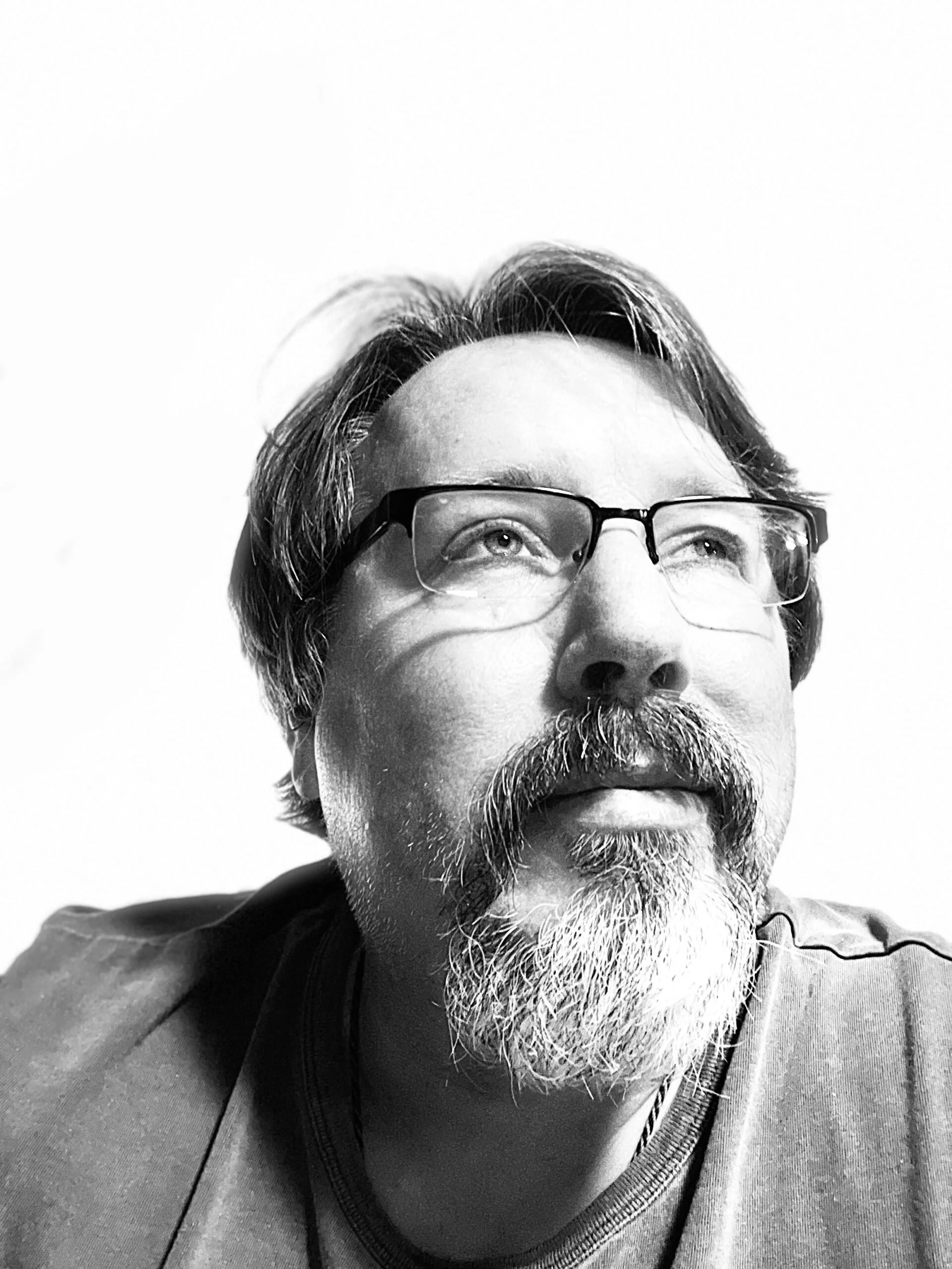 A black and white image of a man looking up, smiling softly