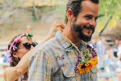 A man smiling with sunflowers around his neck