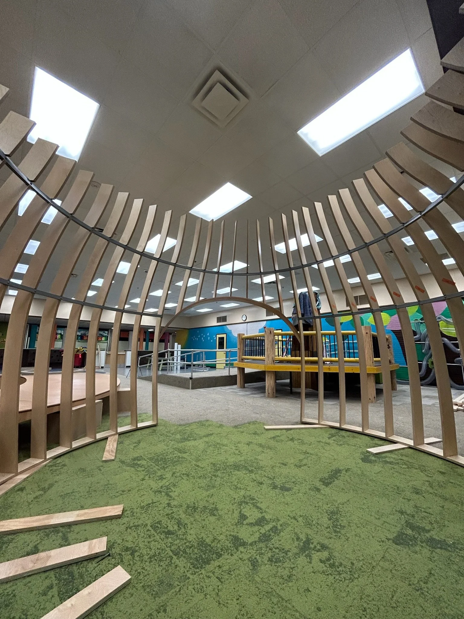 Indoor playground with wooden structure and green carpet