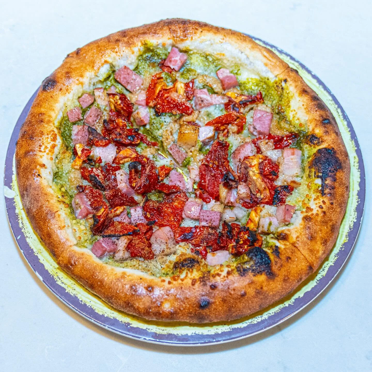 We made a pizza with pesto, roasted garlic, pancetta, sun-dried tomatoes, pecorino, and garam masala.
It&rsquo;s called the Mughal Margherita.
No, we didn&rsquo;t run this by Italy first.. oh well it&rsquo;s delicious!

Mughal Margherita
Pesto base p