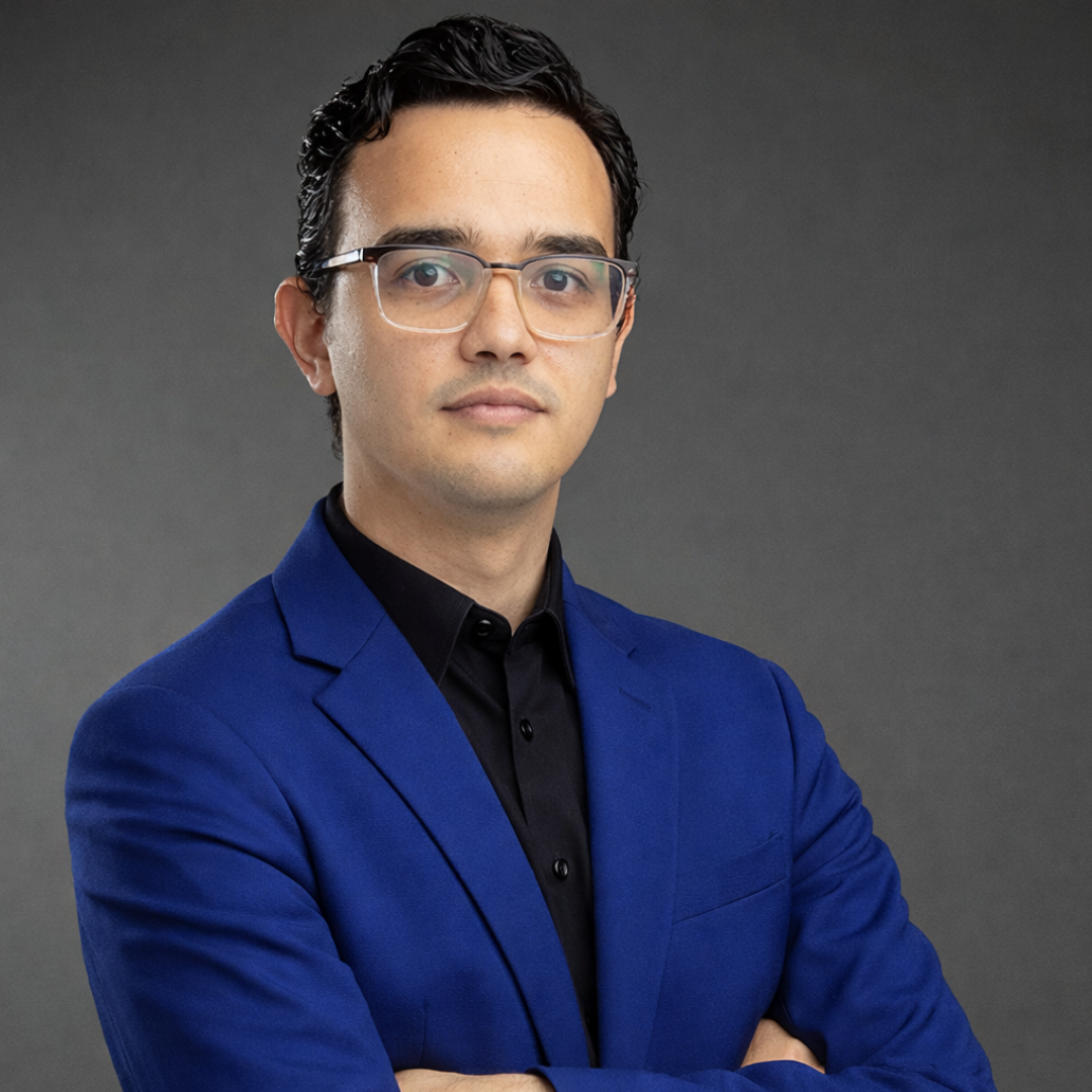 Young man wearing glasses, white shirt, and black tie with logo.
