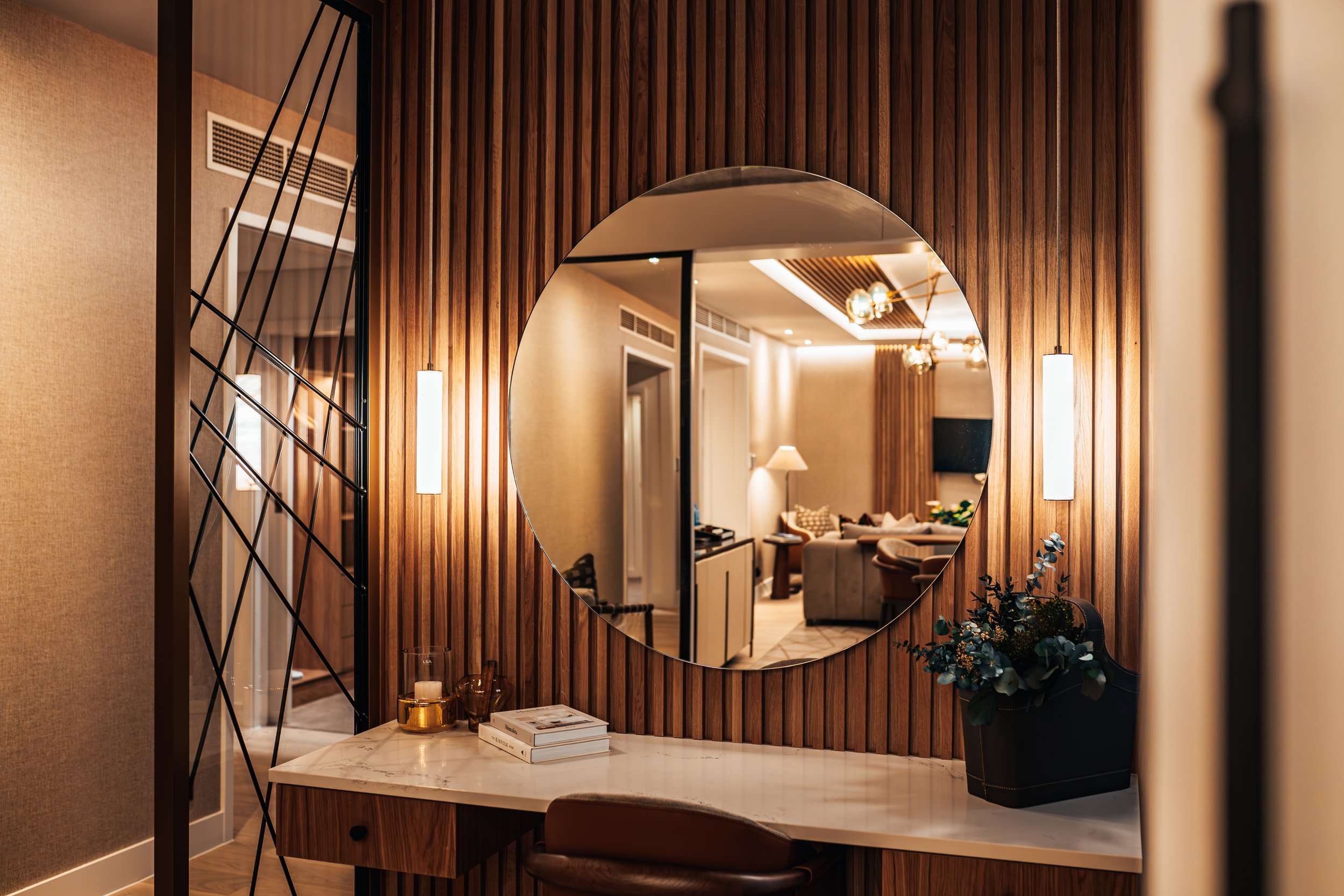 Decorative wooden wall with a large circular mirror reflecting a cozy living room and sitting area.