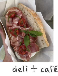 Bread sandwich with sliced cured meat, cherry tomato slices, and fresh basil leaves