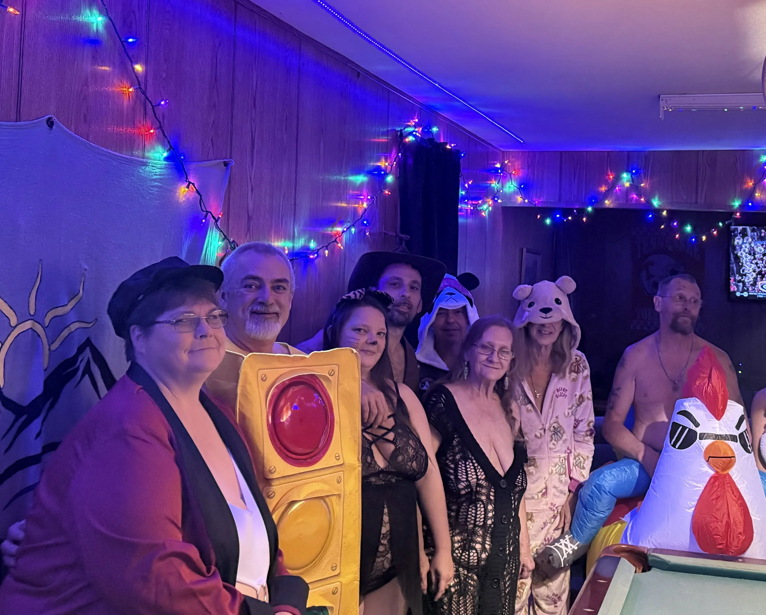 People dressed in costumes at a party with colorful string lights on the walls and ceiling