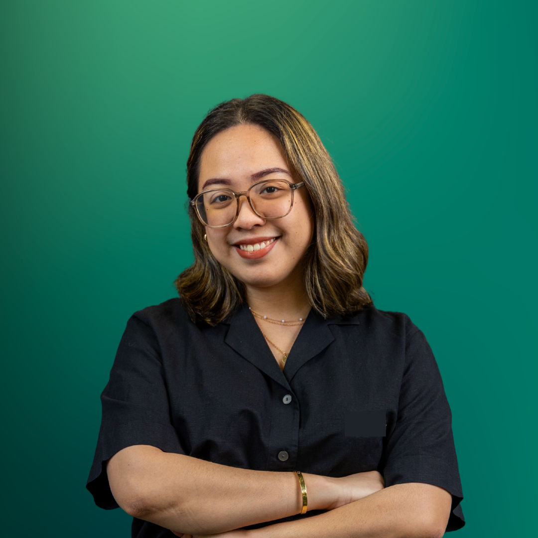 A woman with shoulder-length hair, wearing glasses and a black shirt, smiling with arms crossed against a green gradient background.