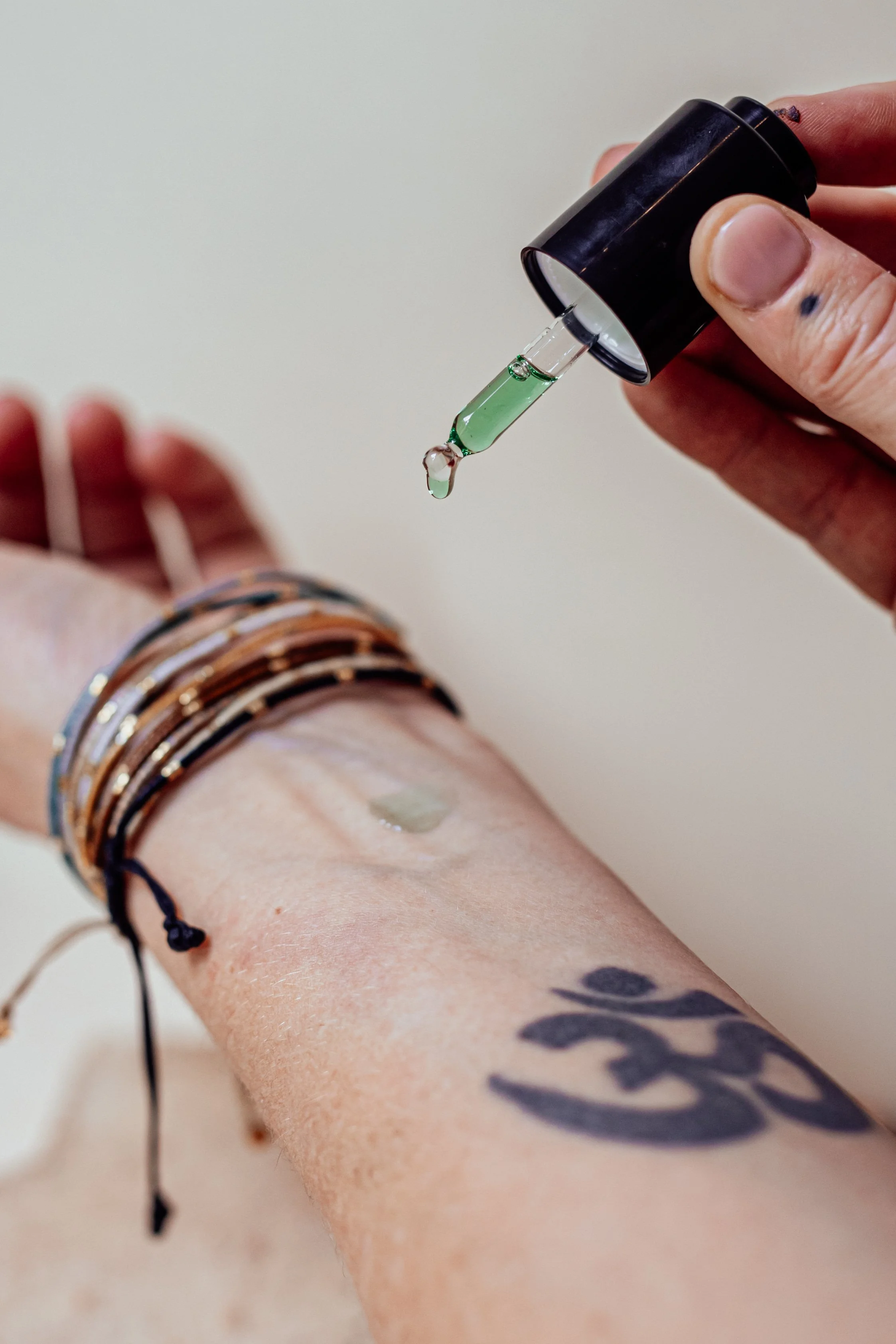 Applying Sanctus Vetiver oil to wrist — emerald-green Vetiveria zizanioides (Khus) in jojoba, wild-harvested in India