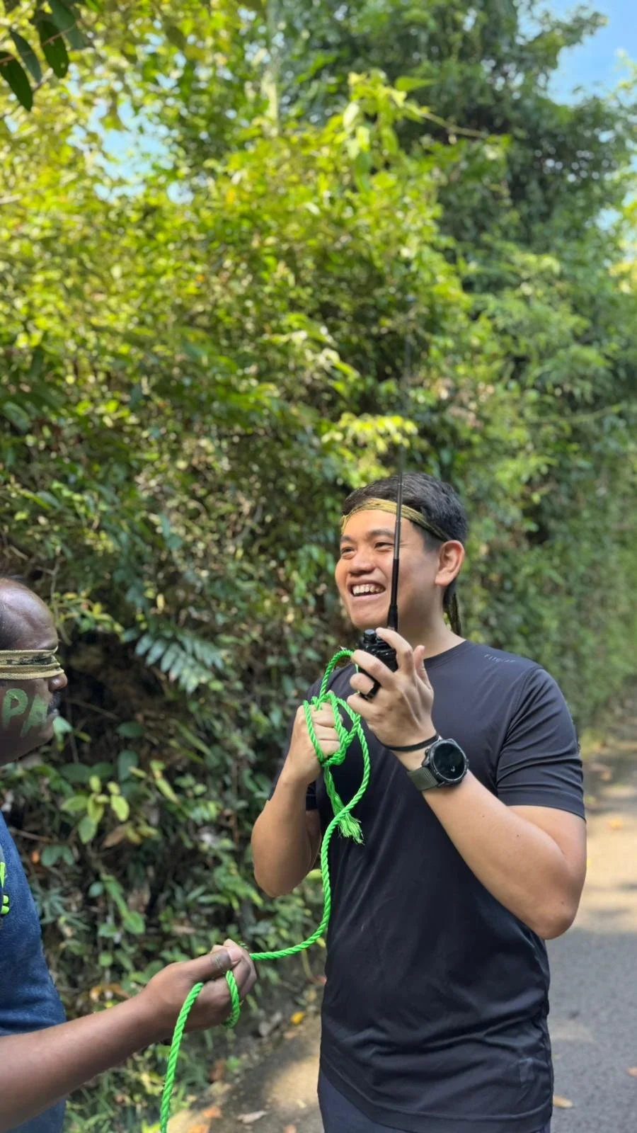 Participant holding green rope during a hands-on outdoor challenge at Fort Serapong