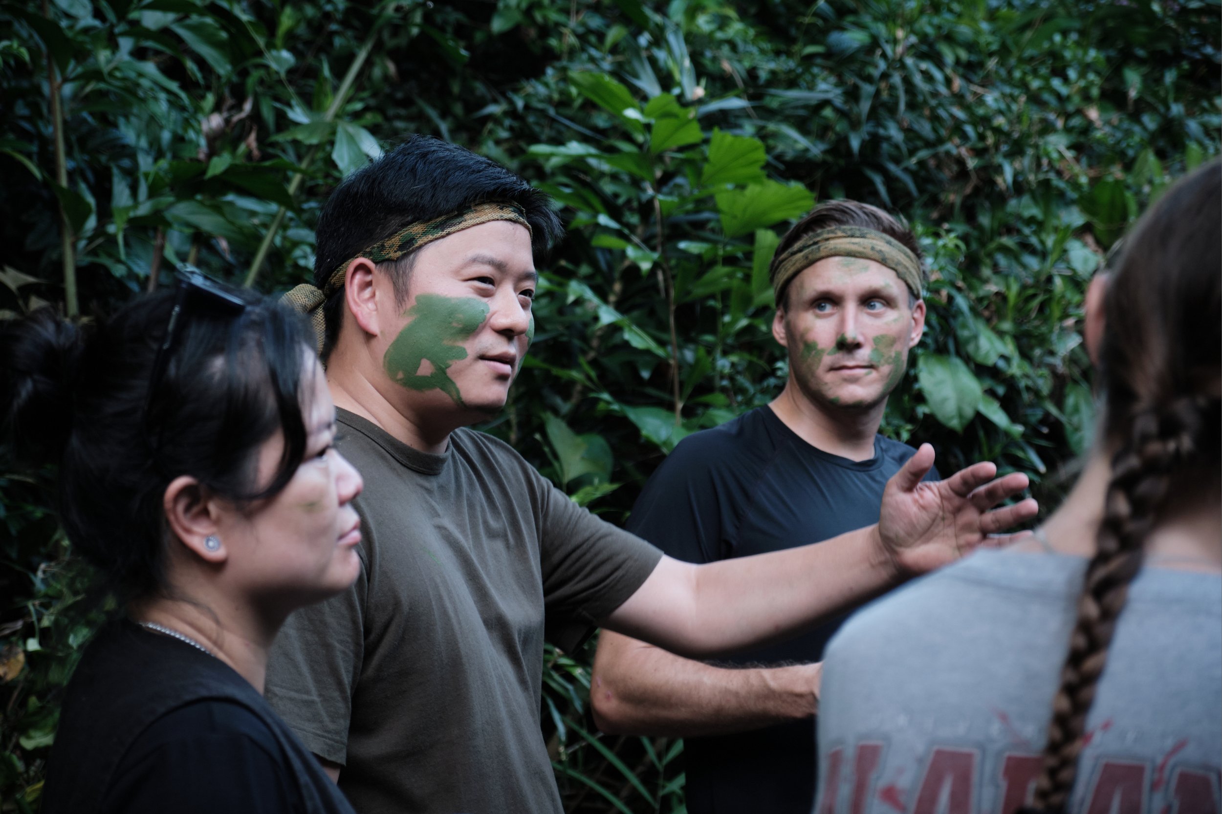 NORDEN colleagues with heritage face paint discussing a task during their Fort Serapong team bonding mission in Singapore