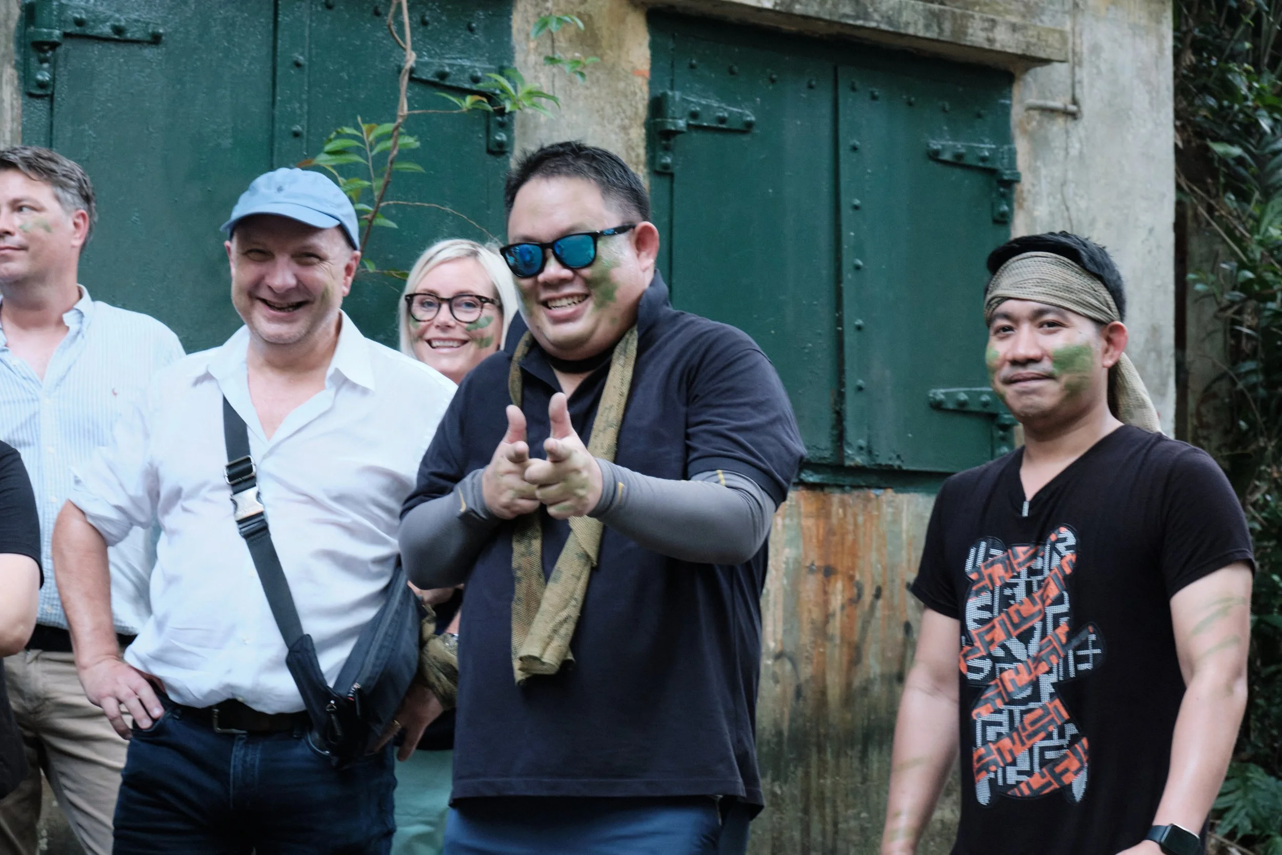 Corporate group with heritage face paint posing by the fort doors during a team bonding day at Fort Serapong, Singapore