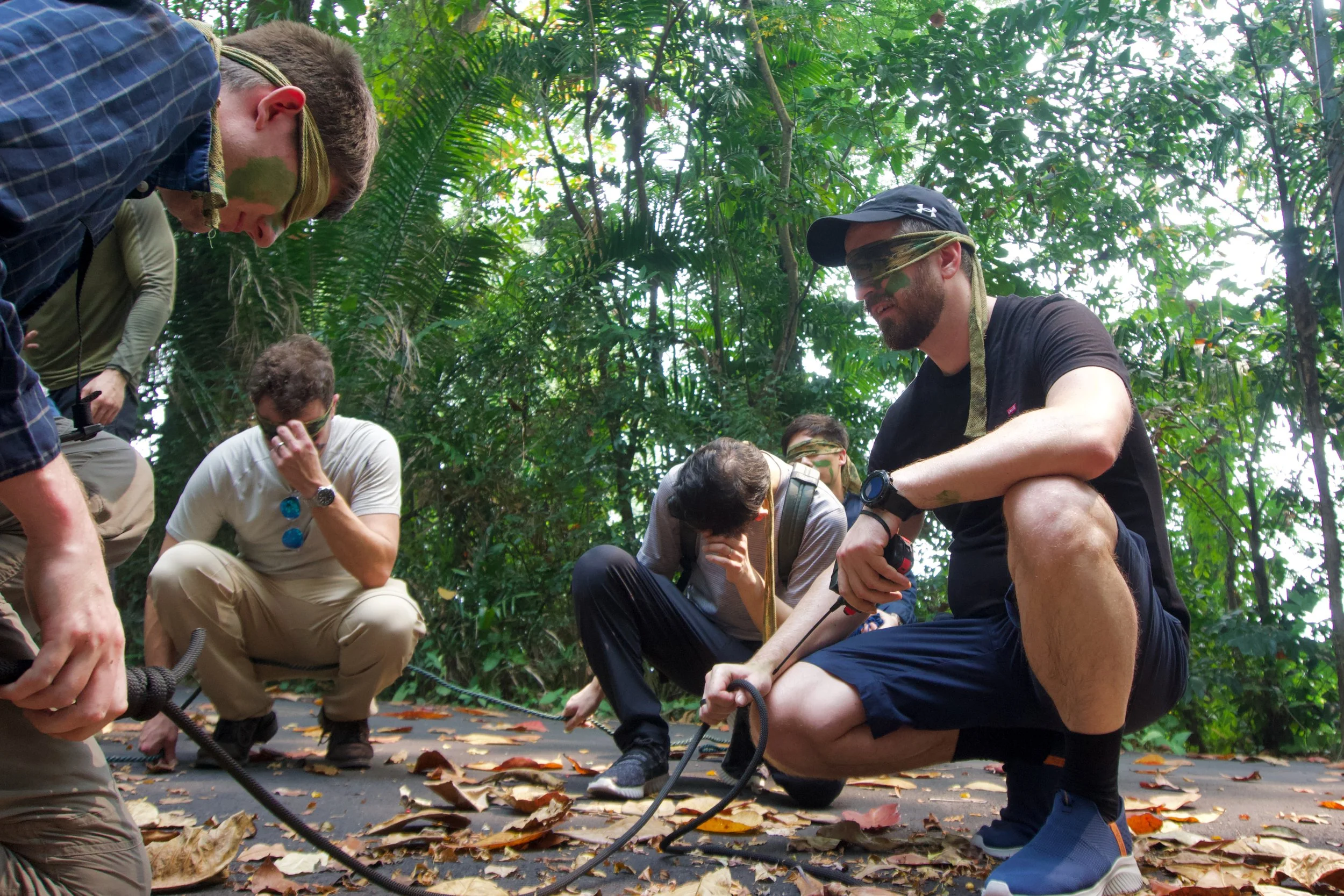 Citadel Securities participants crouched over rope and equipment on a forest track