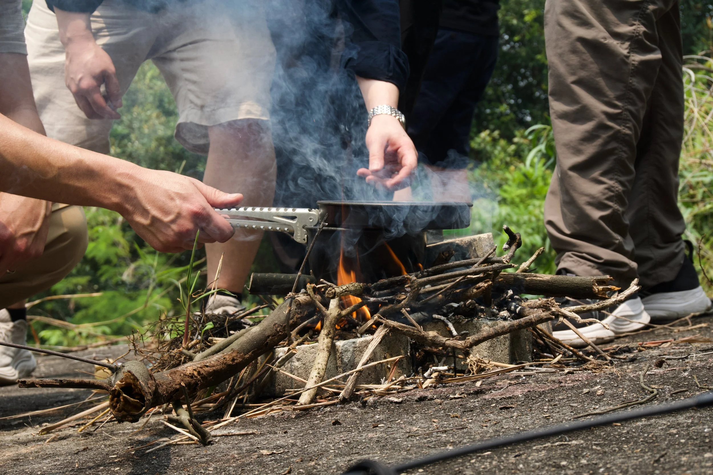 Smoke rising from a stick fire at Granite Hill as participants feed fuel into the flames, Fort Serapong.