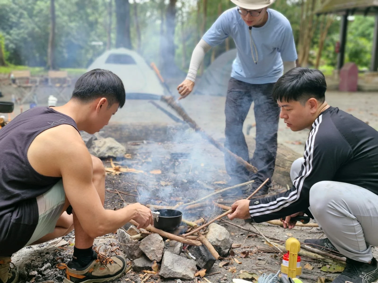 Friends cooking together around a campfire at Pulau Ubin