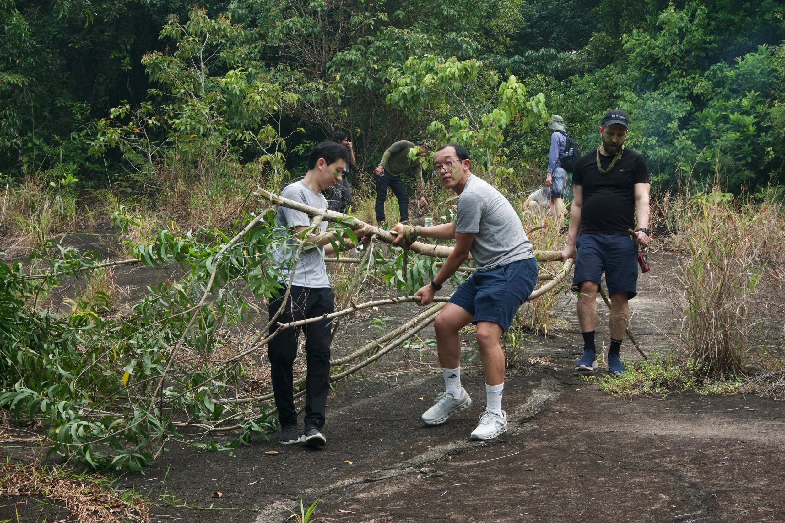Participants positioning branches at Granite Hill during the natural shelter challenge at Fort Serapong.