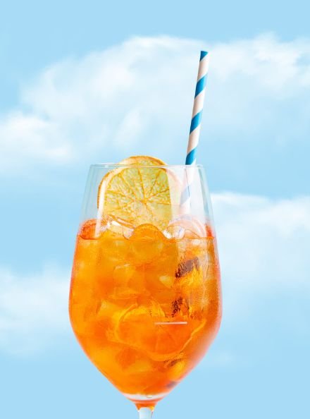  A sparkling onrange cocktail ona sunny blue sky background 