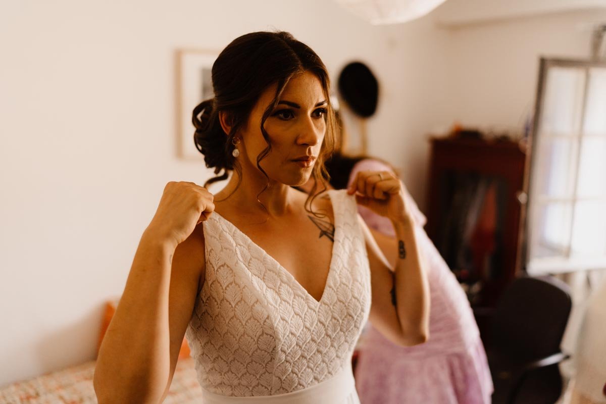 Femme portant une robe de mariage, ajustant les bretelles, cheveux relevés.