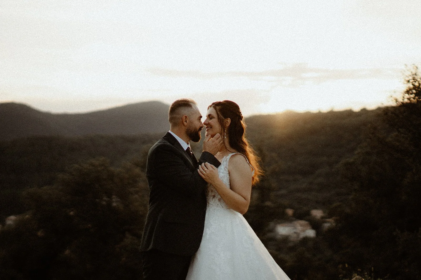 Un couple de mariés souriant lors d'un coucher de soleil en plein air.