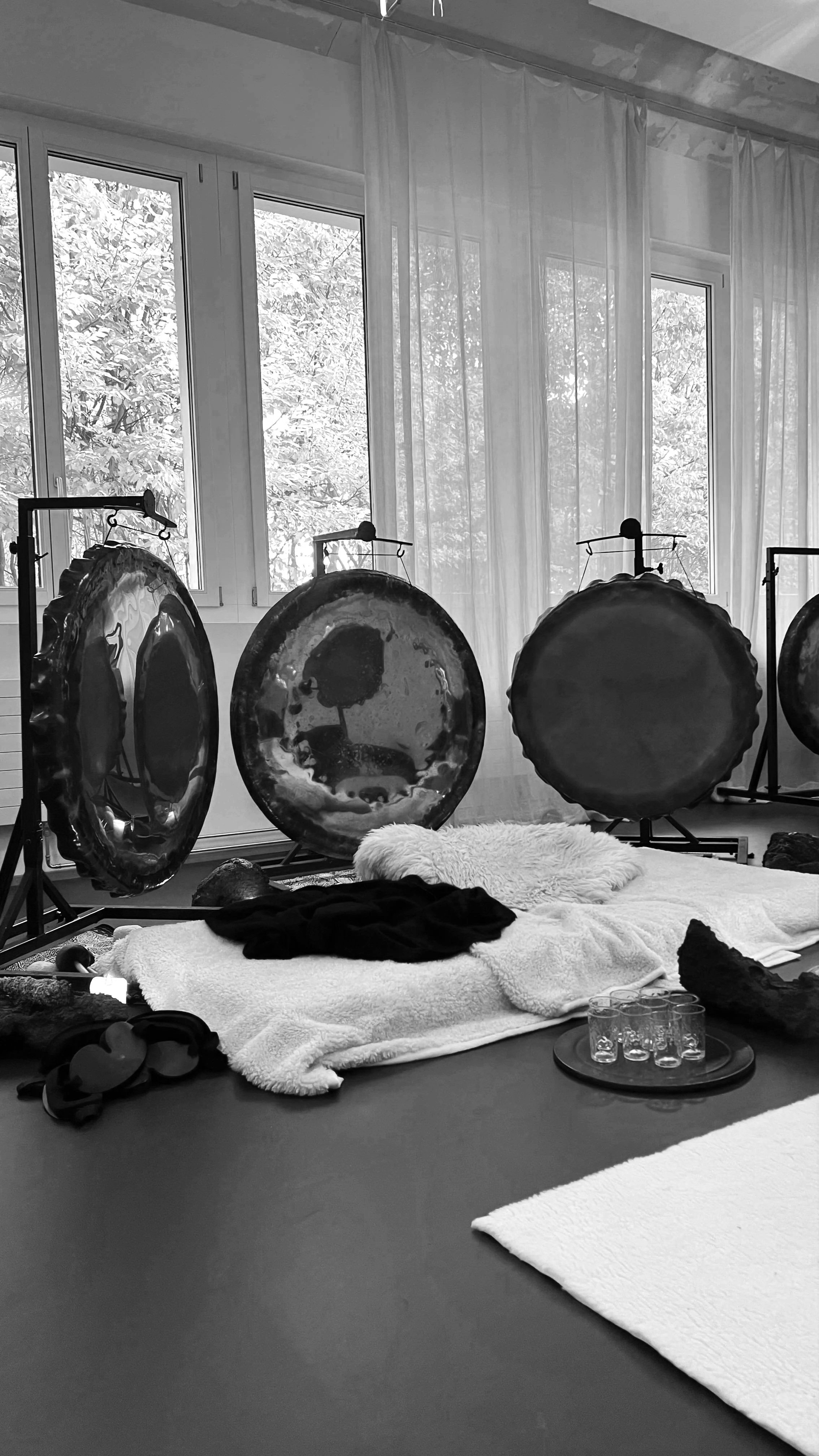 Room set for a gong hypnosis session with gongs, sheepskins and water