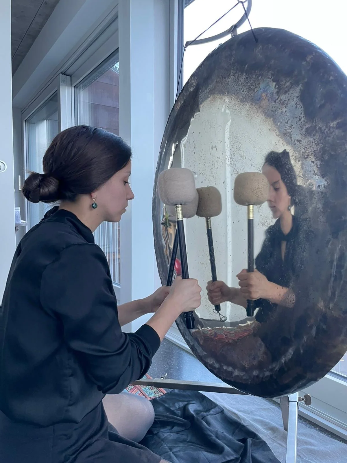 Rocío playing the MeteoriteGong with two mallets during a gong hypnosis session