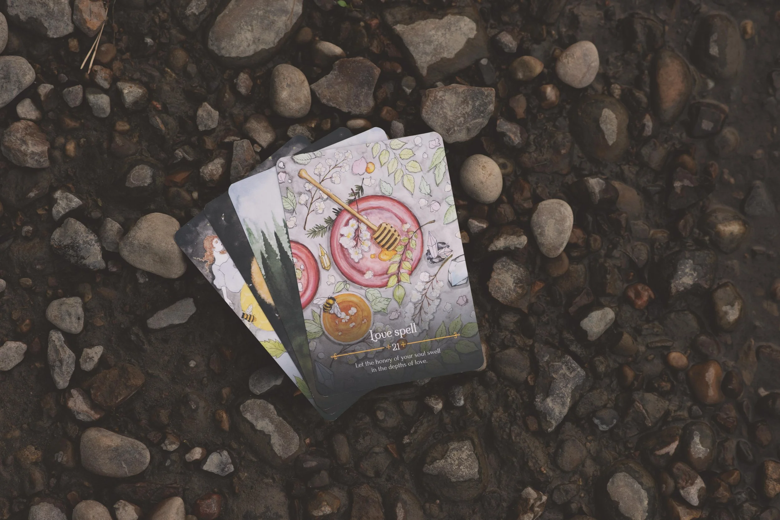 love spell oracle card laying on river rocks