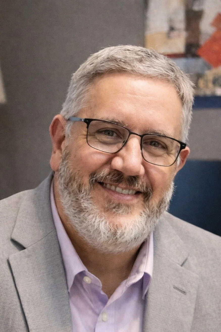Mark Nickerson, leadership coach and founder of Leading With Meaning, smiling in an office setting.