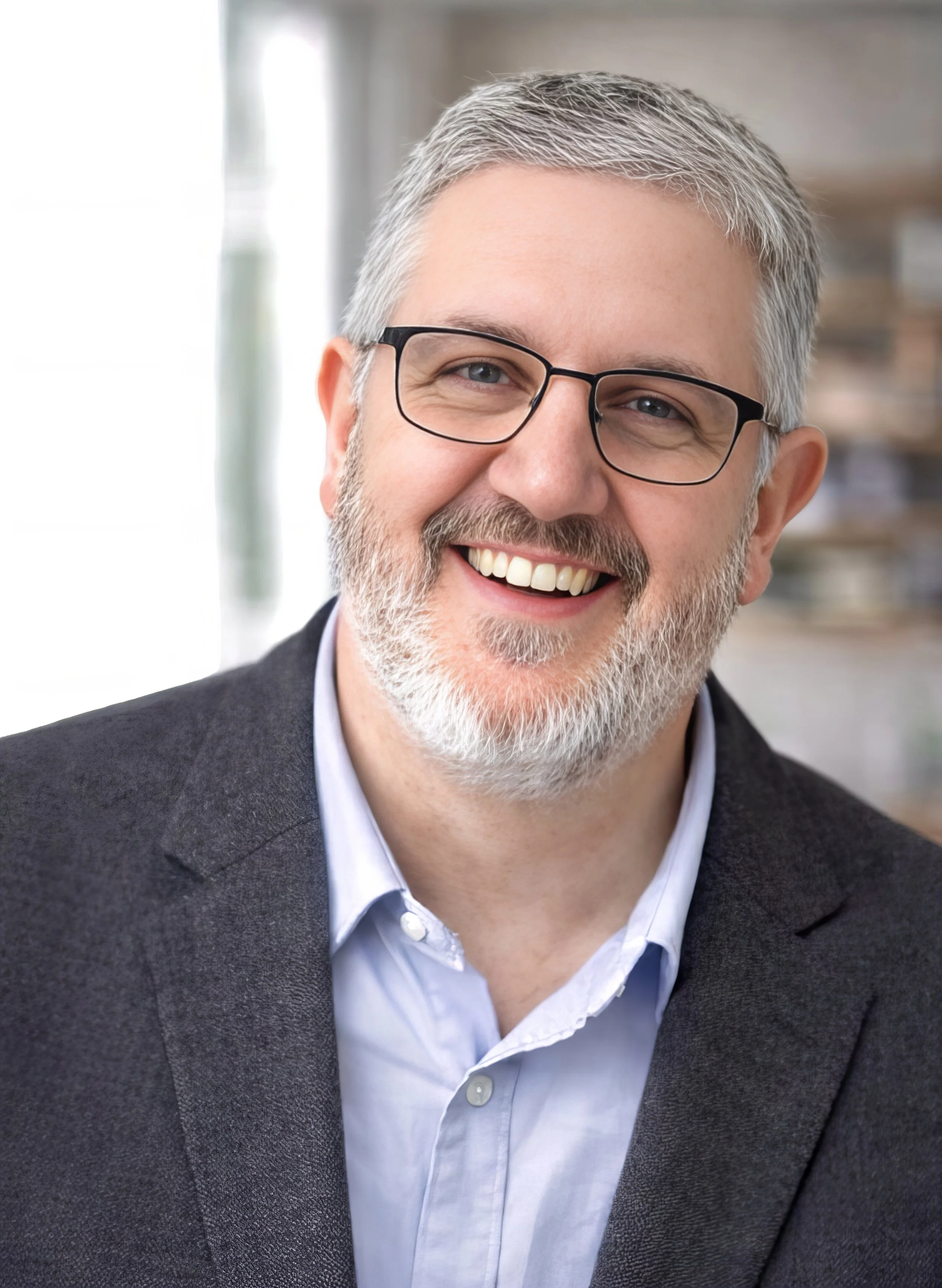 Mark Nickerson, leadership coach and founder of Leading With Meaning, smiling in an office setting.