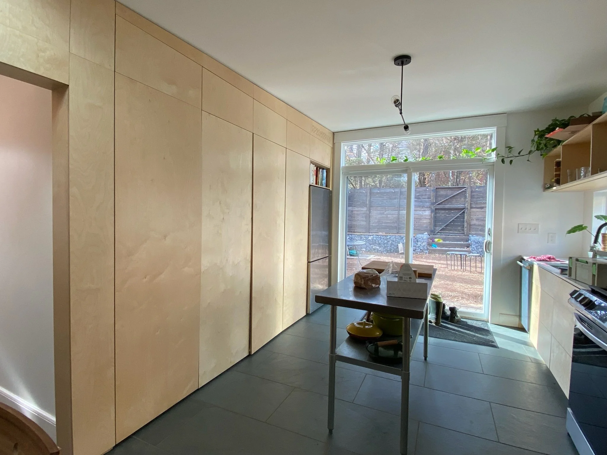 Interior renovation with floor-to-ceiling Baltic birch paneling and flush cabinet doors. One set of doors retract into concealed pockets to reveal a coffee bar.