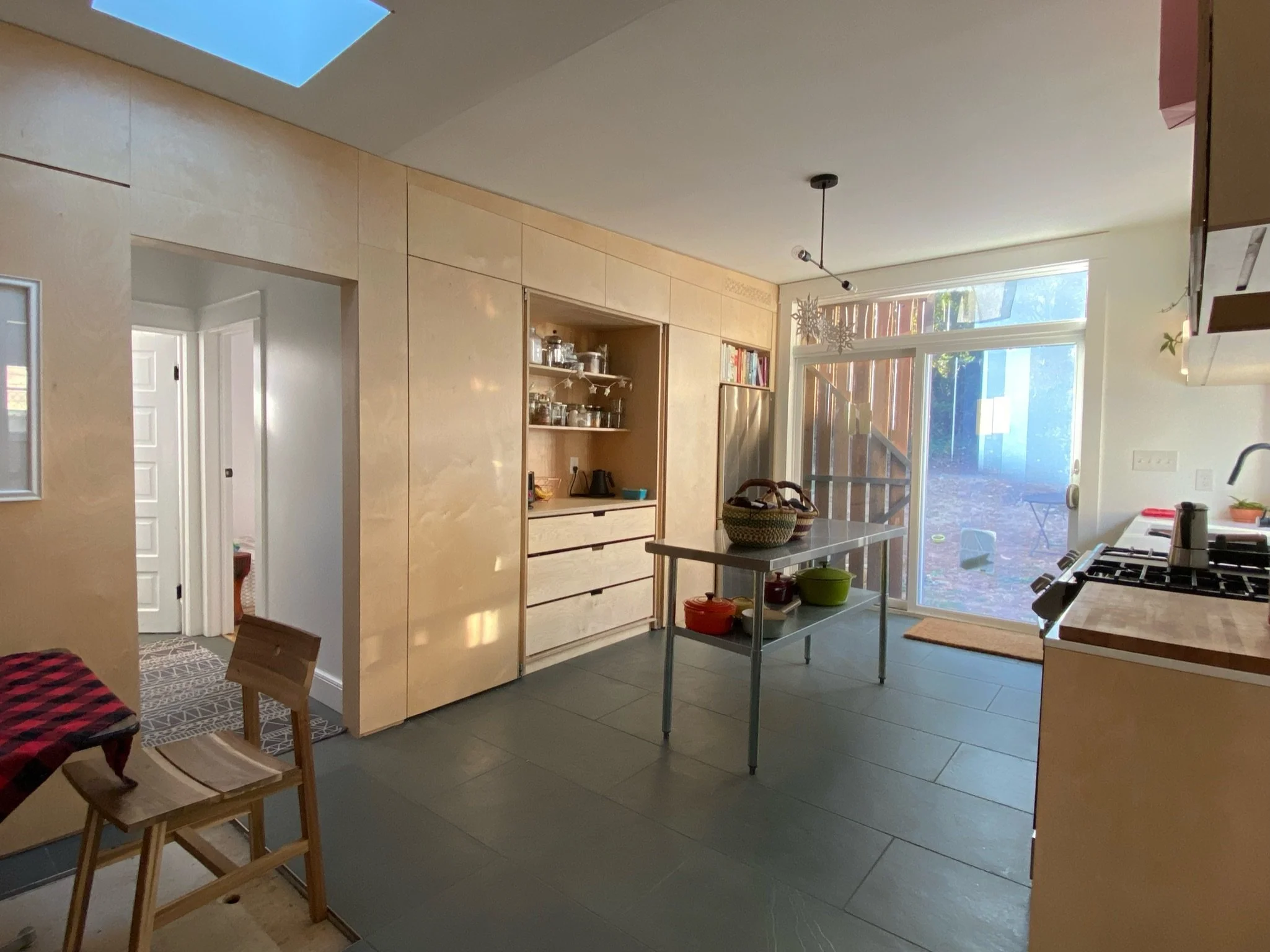 Interior renovation with floor-to-ceiling Baltic birch paneling and flush cabinet doors. Coffee bar doors open.