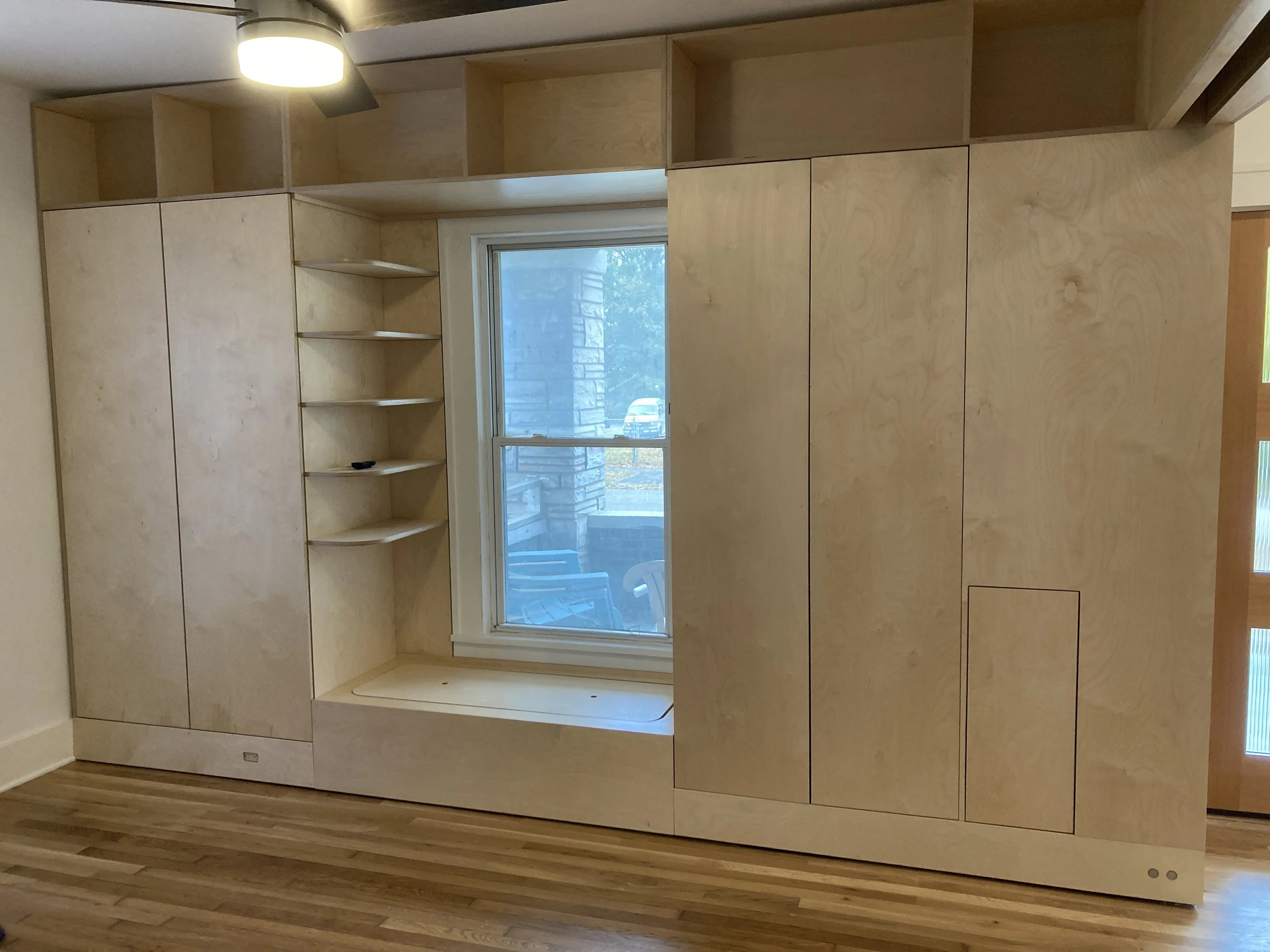 Custom storage solutions in the study include overhead book storage, three spacious cabinets, and under bench storage. The pocket door magnets can be seen mounted to the toe kick bottom right.