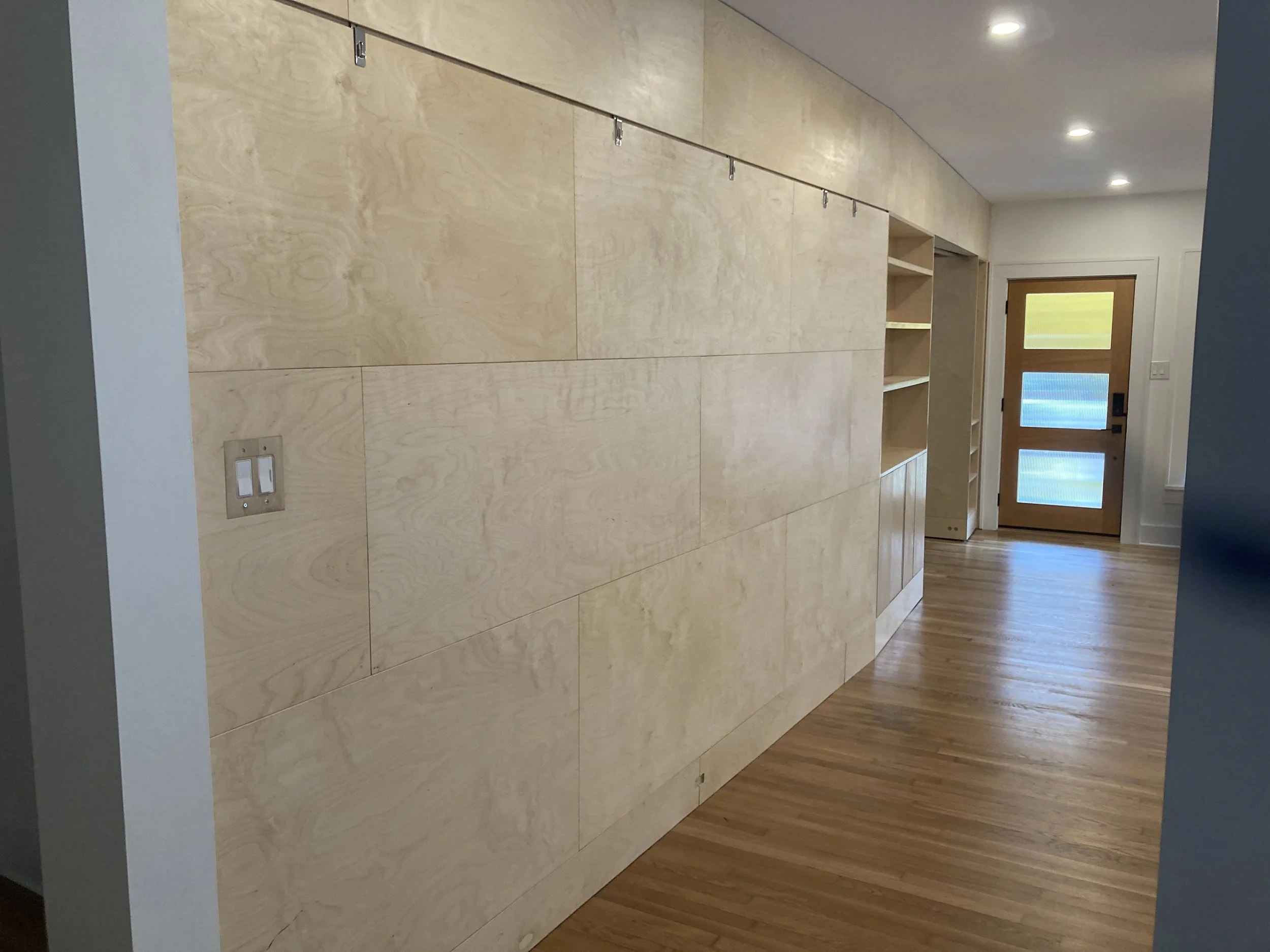 Interior renovation featuring staggered Baltic birch panels, an adjustable art rail, and custom storage solutions.