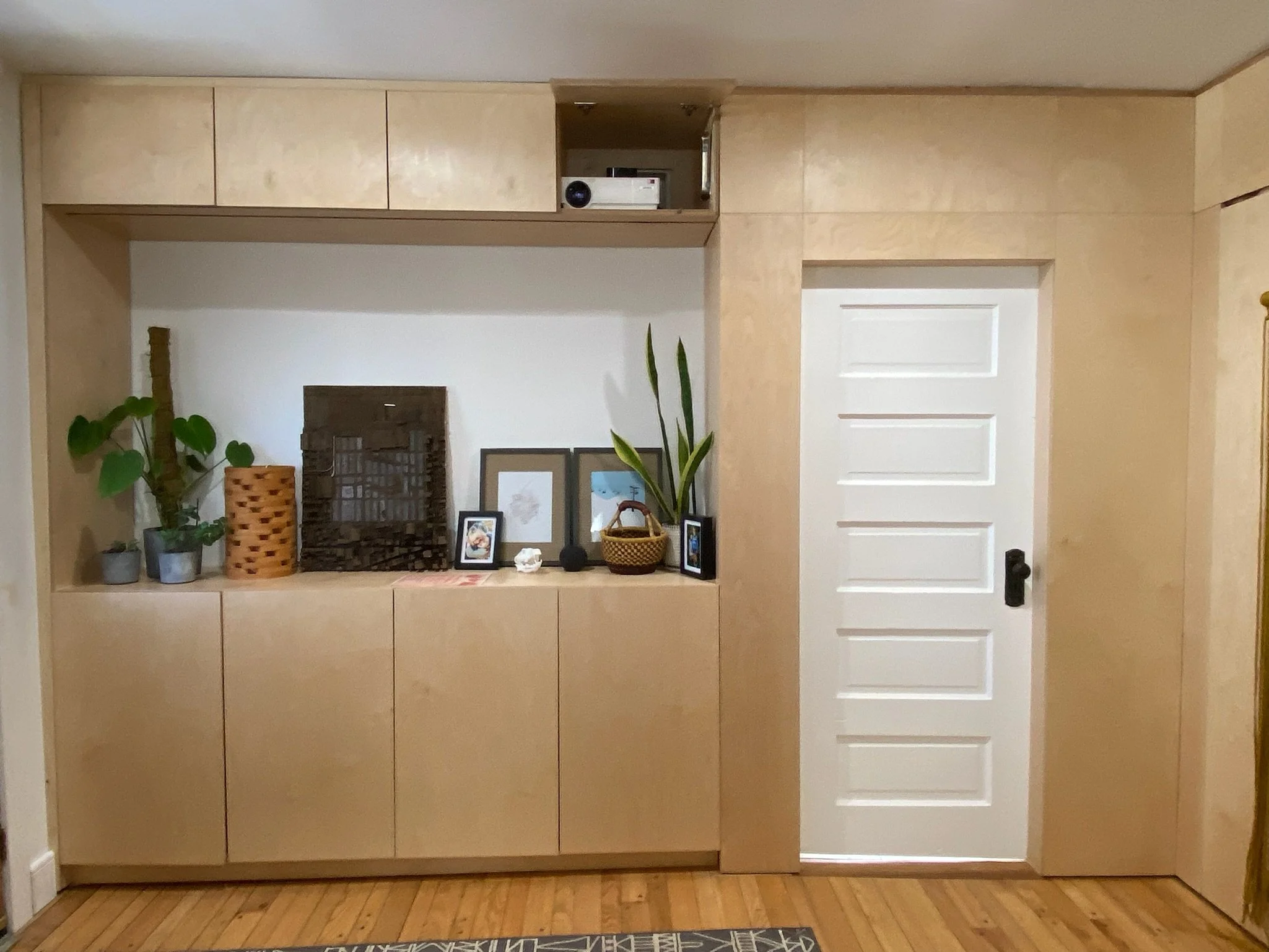 Interior renovation with floor-to-ceiling Baltic birch paneling and flush cabinet doors. This entry feature provides storage for shoes, books, and an overhead projection station.