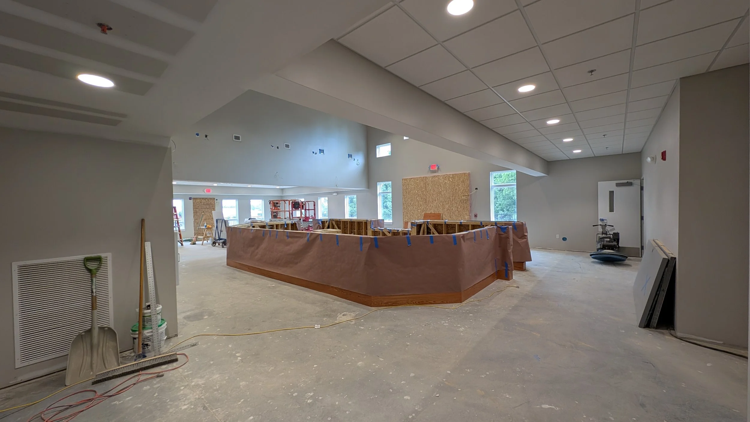 Interior view of a room under construction with tools, construction materials, and a partially enclosed area in the center.