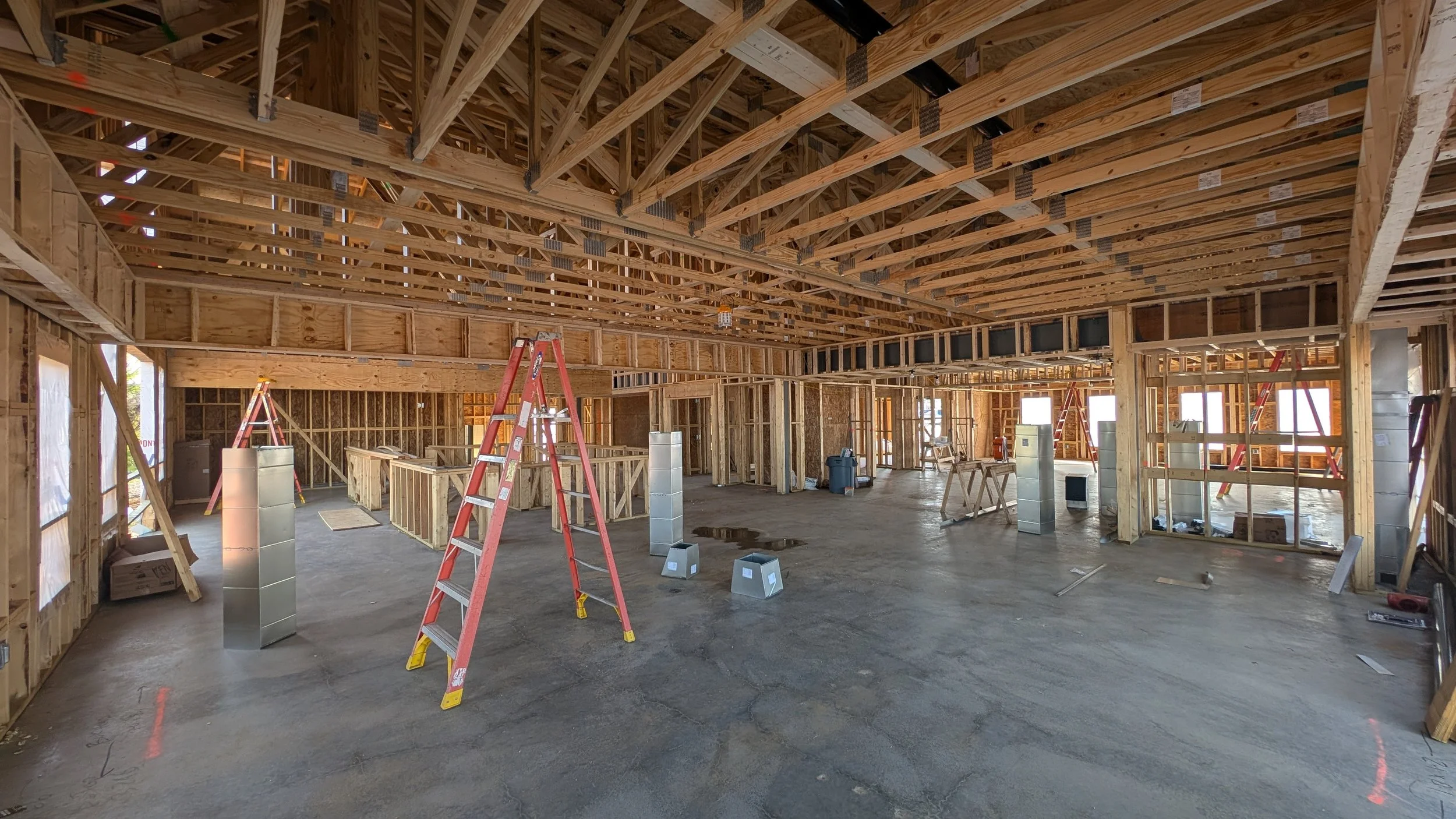 Construction site of a building with exposed wooden framework, ladders, and construction materials inside