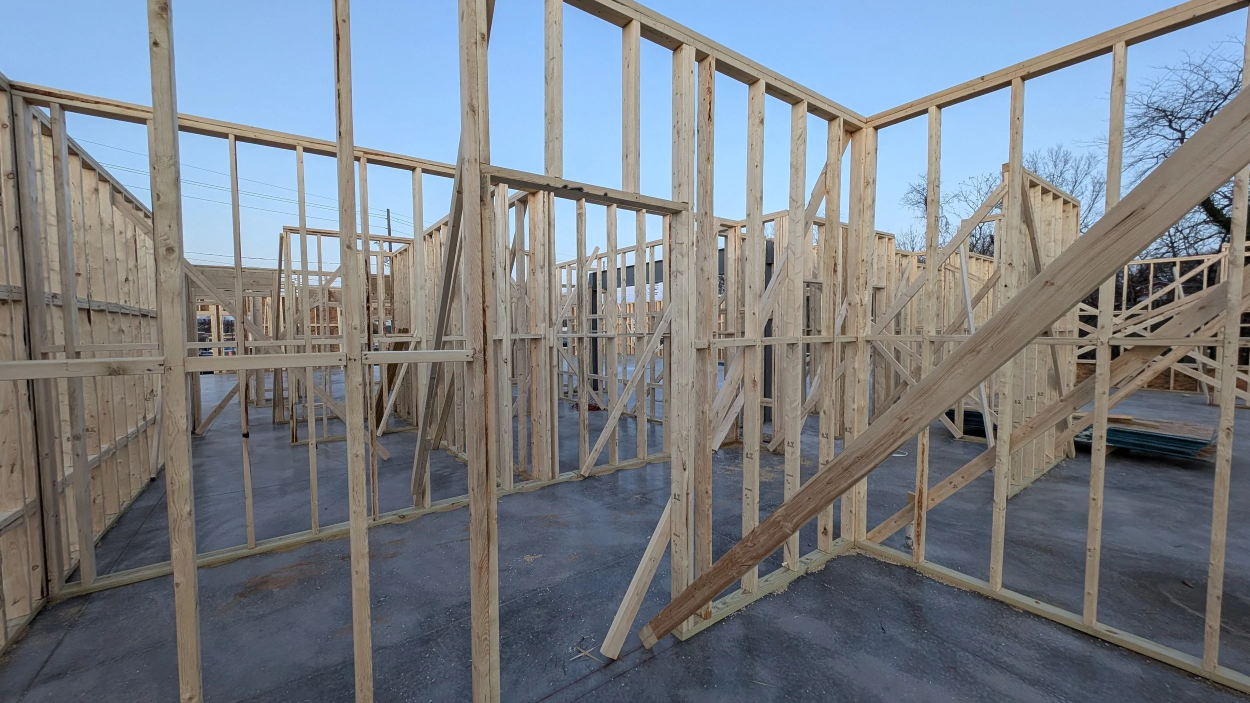 Wooden framing for a building under construction with clear blue sky.