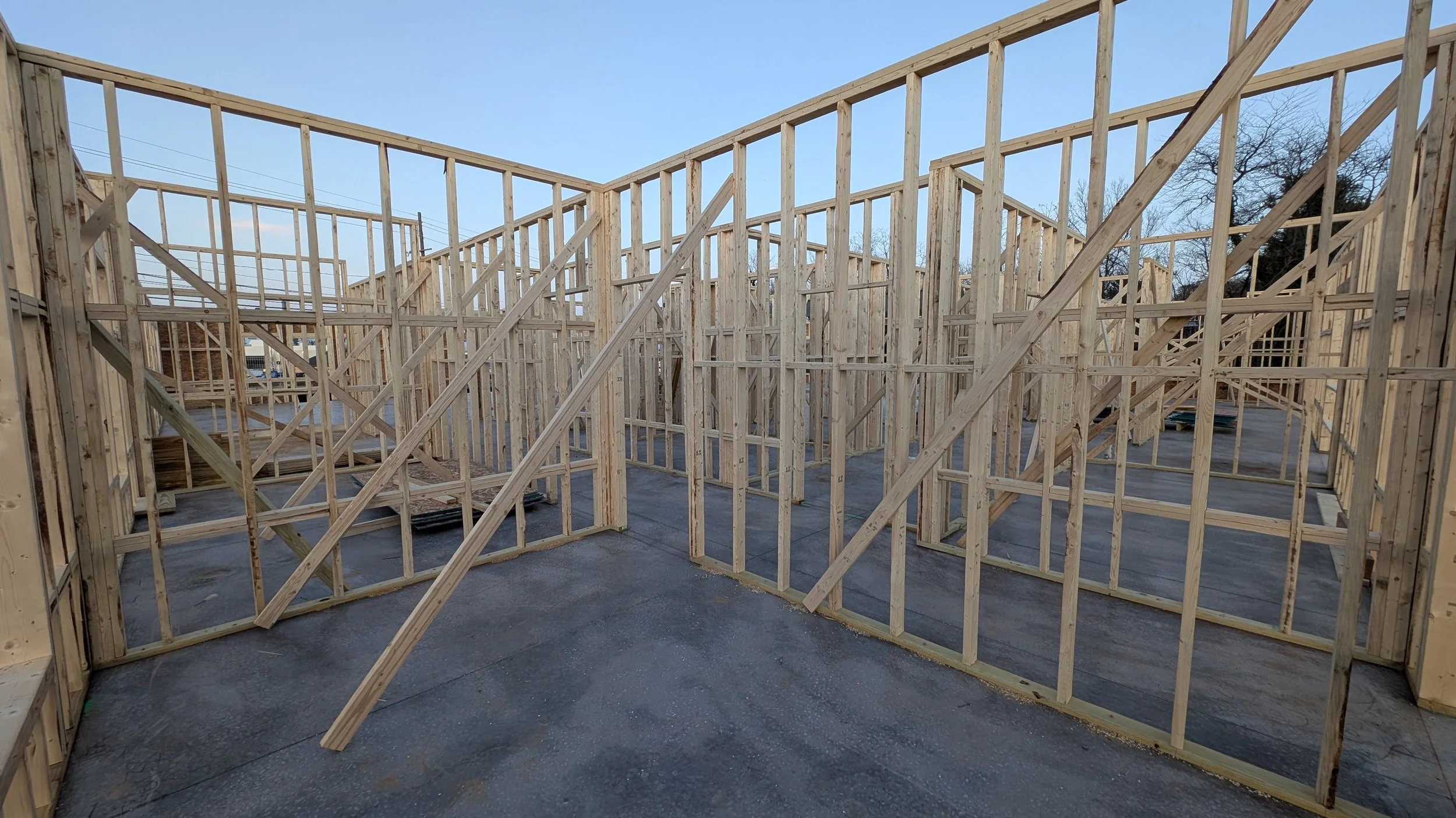 Wooden framing of a house under construction, showing walls and support beams on a concrete foundation.