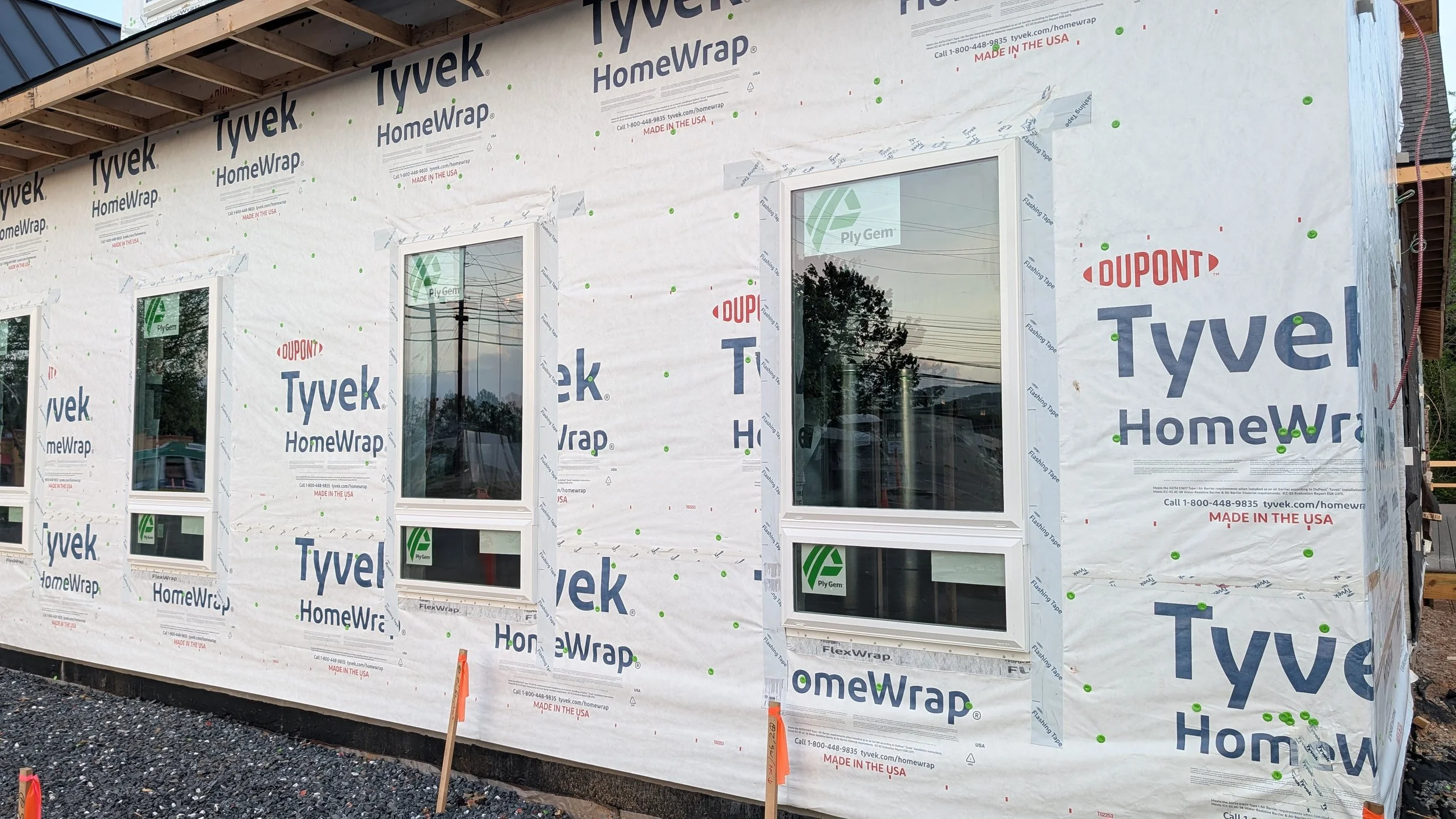 Exterior of a house under construction with window frames installed and house wrapped in Tyvek HomeWrap material.