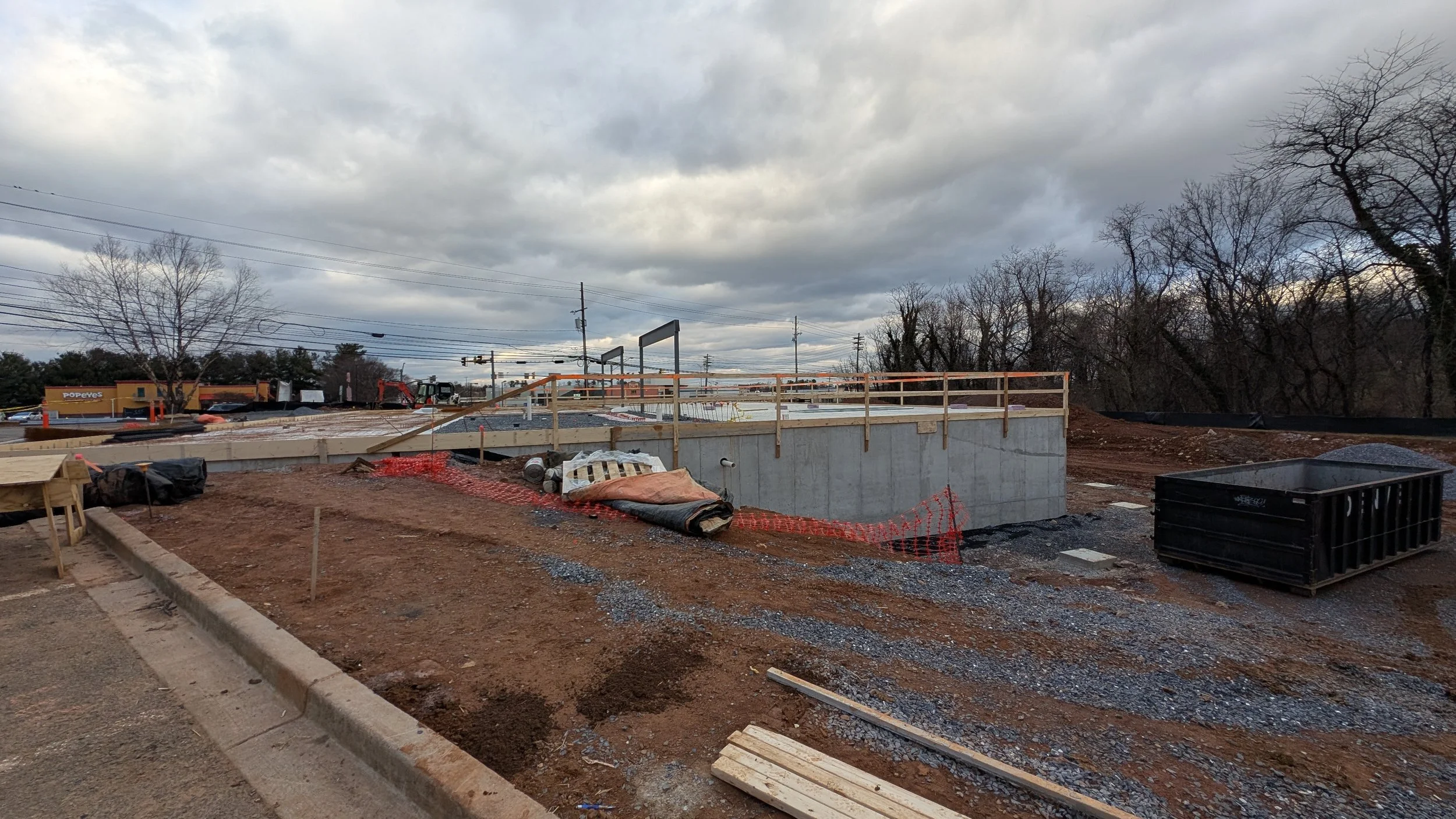 Construction site with foundation in progress and empty landscape under cloudy sky