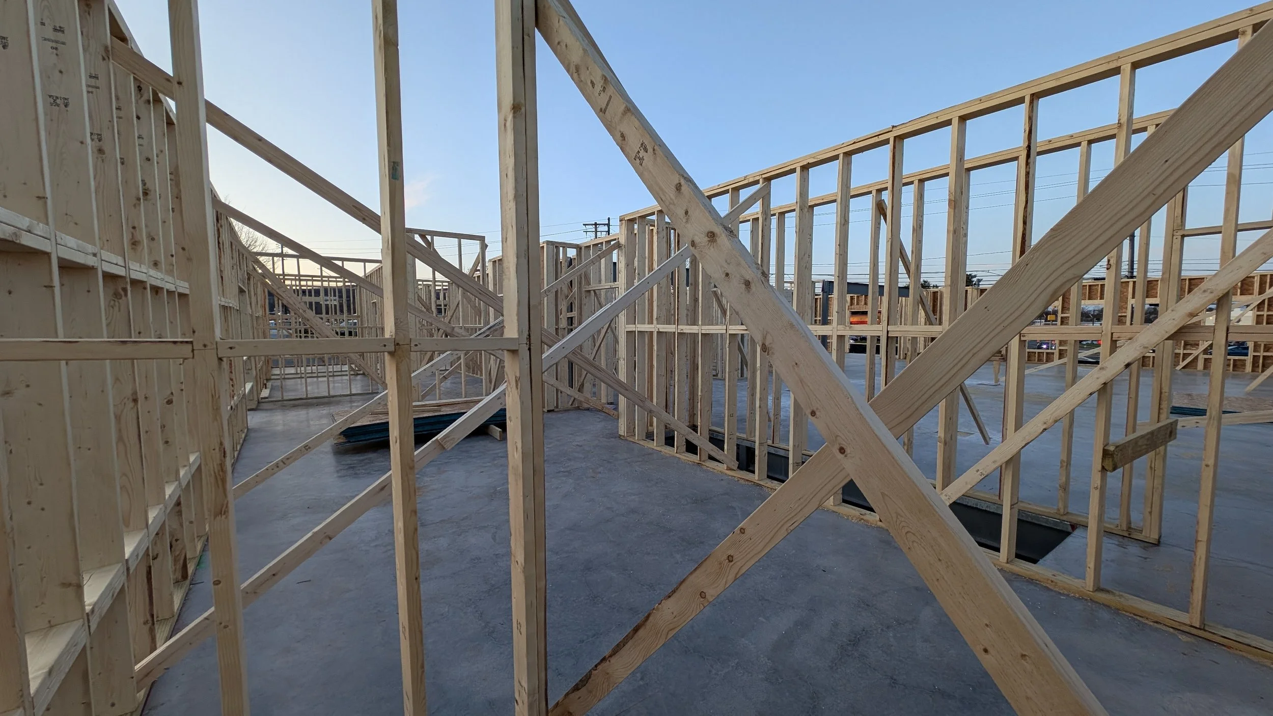 Wooden framing for a building under construction with blue sky in the background.