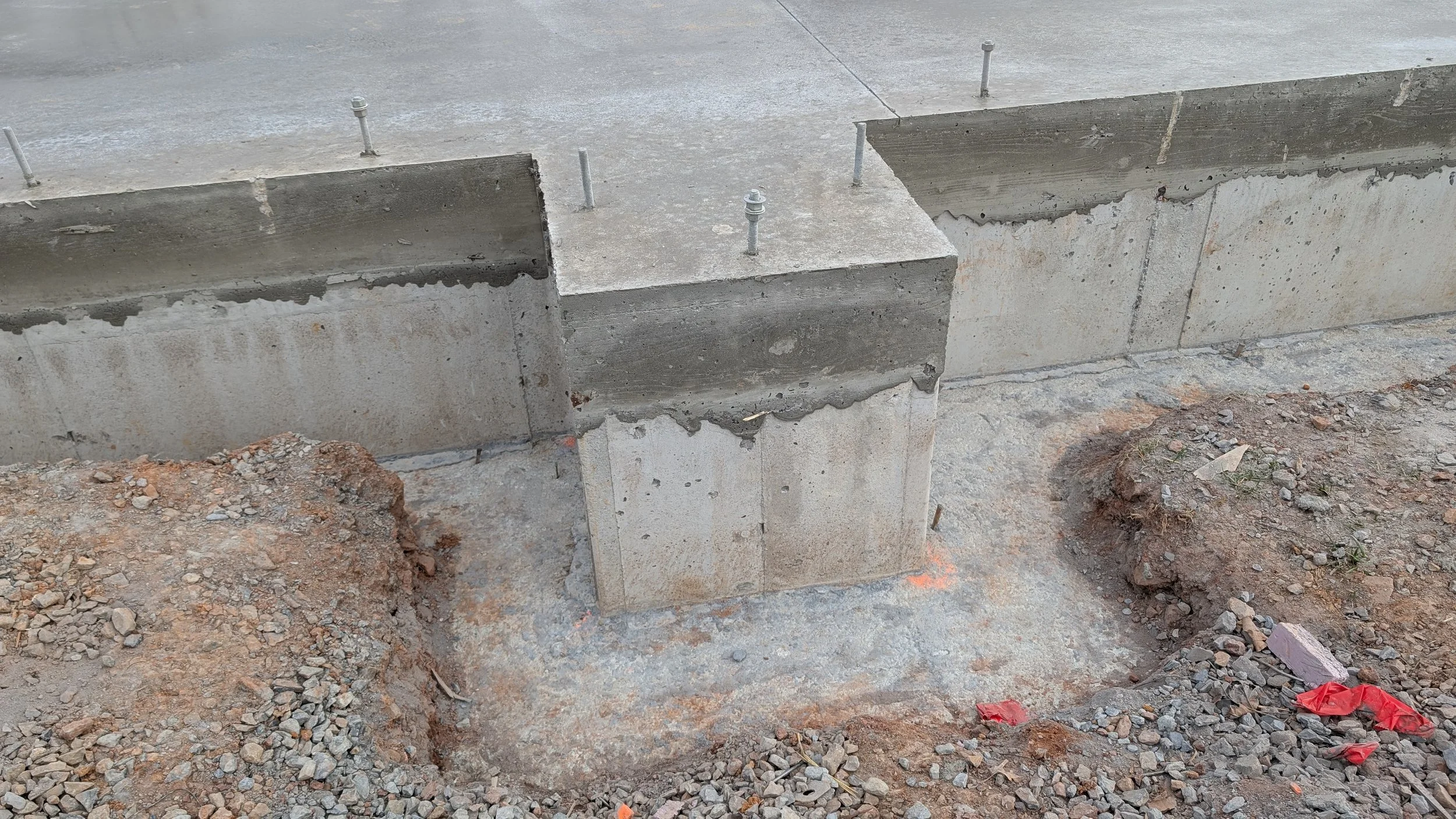 Construction site with concrete pillars and gravel ground.