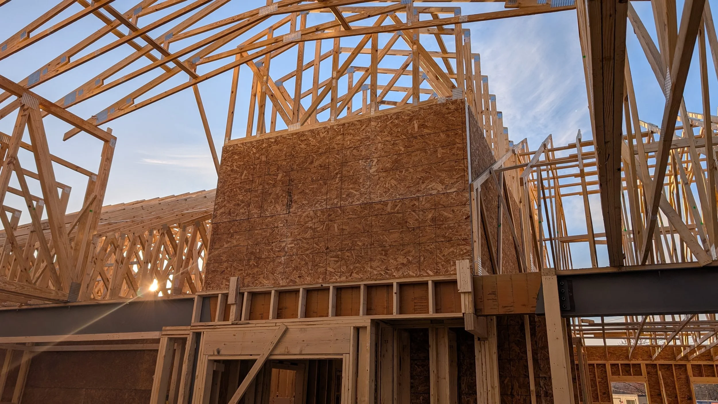 Wooden framing of a building under construction with a clear sky in the background.