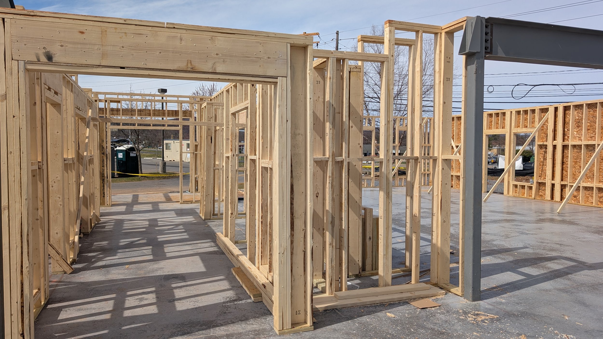 Wooden framing of a building under construction with the foundation visible and some exterior walls partially built.