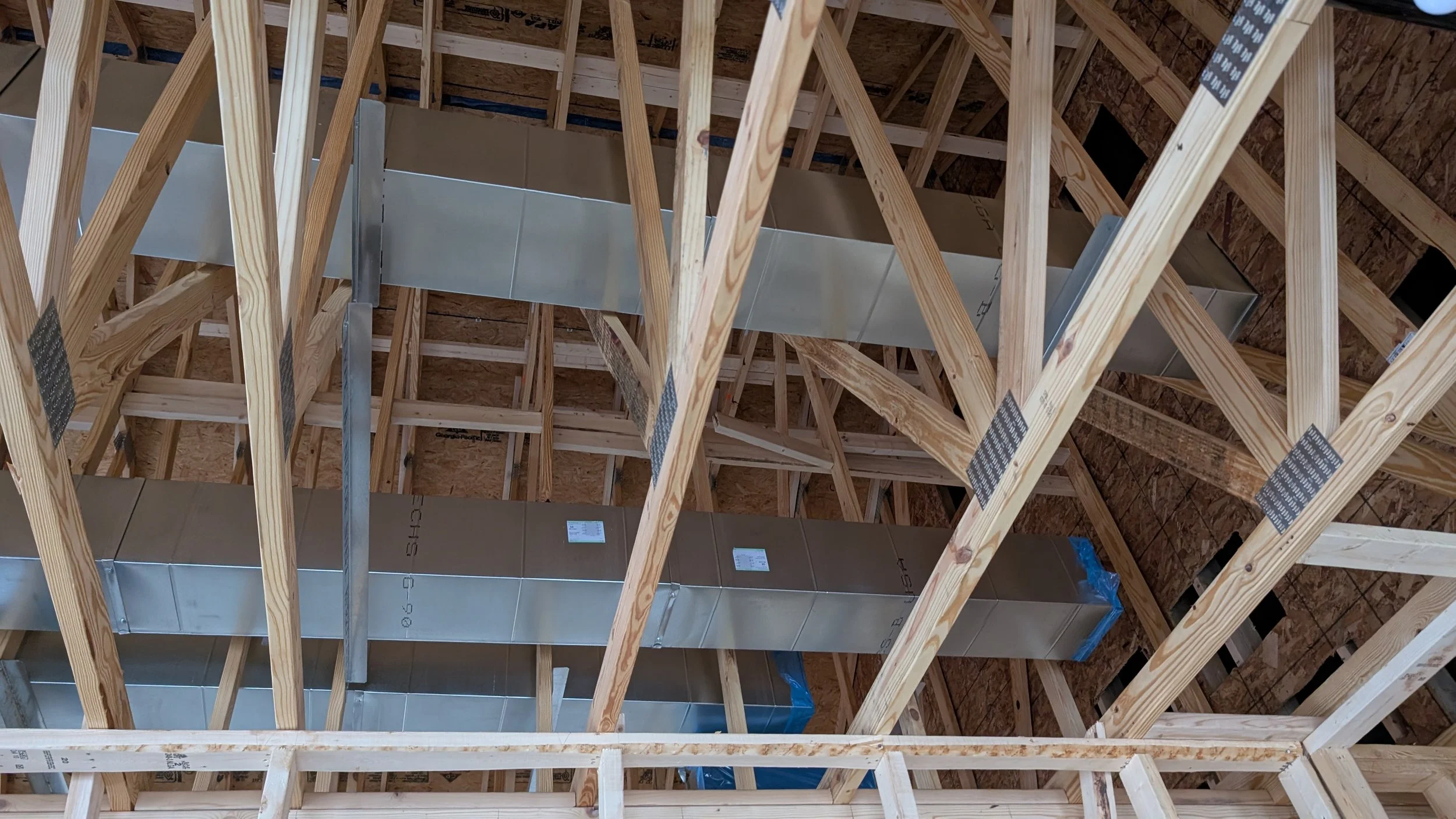 Construction site showing wooden framing and metal ducts for HVAC system in a building under construction.