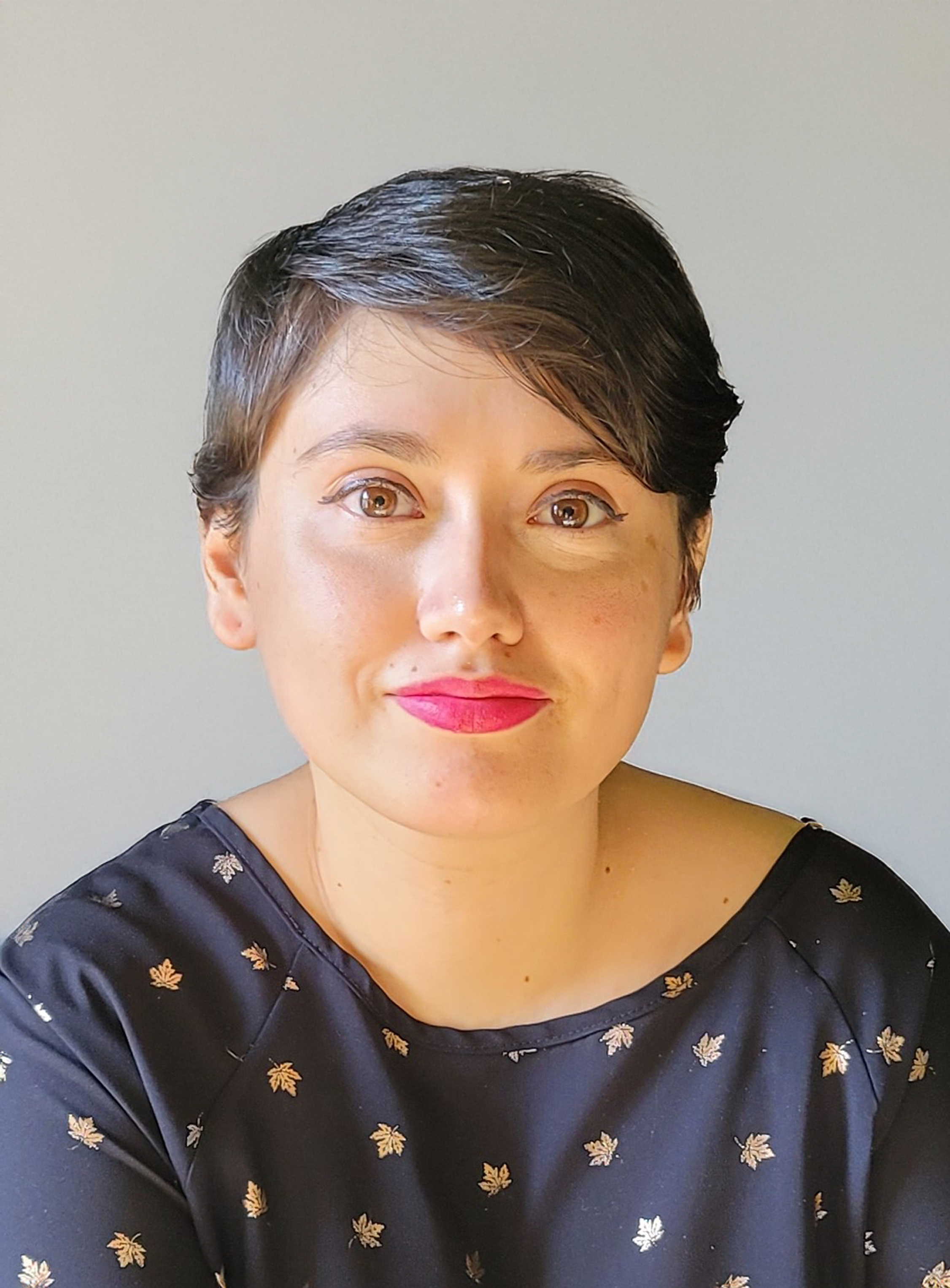 Raquel, professional counselor, smiling against grey background