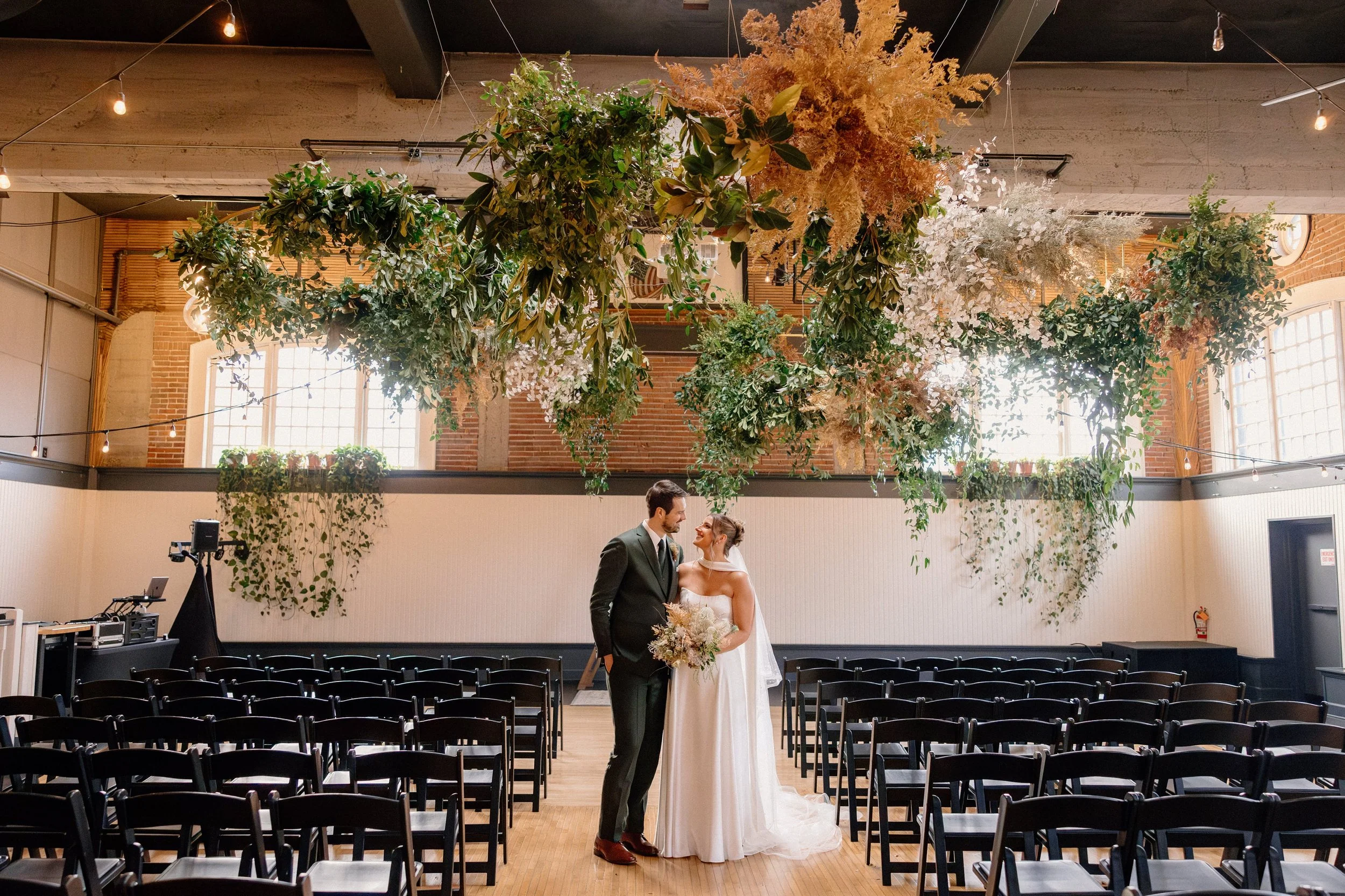 a happy couple standing under a large greenery floral installation