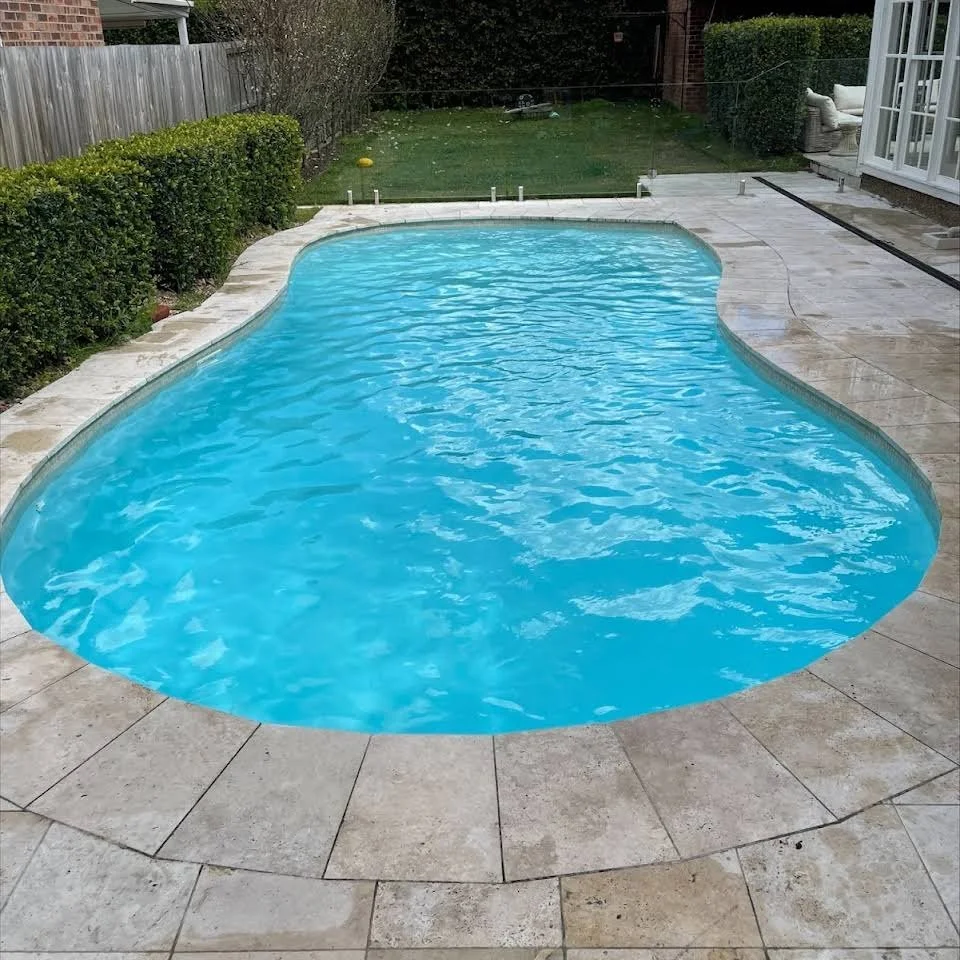A peanut shaped pool in front of grass